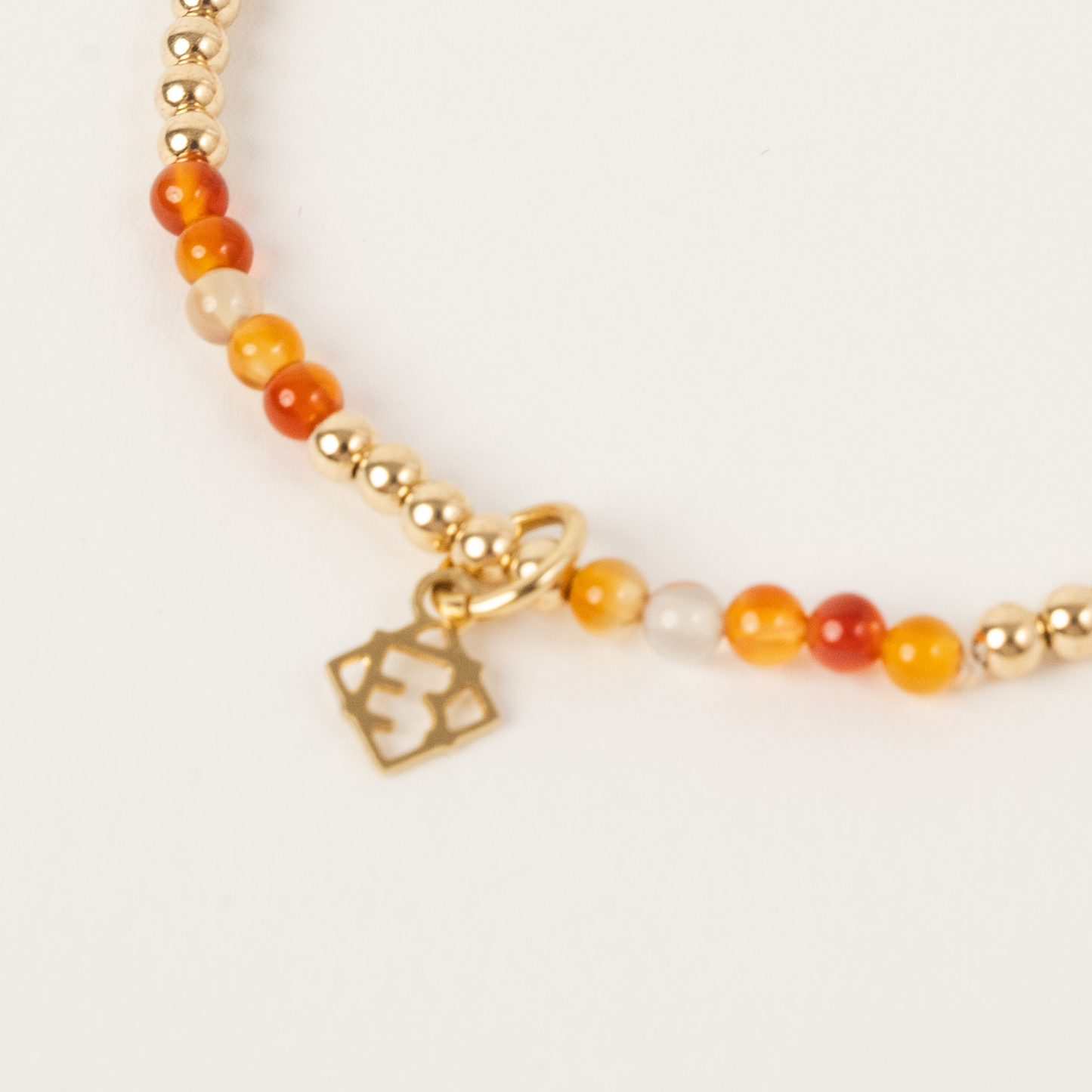 Bracelet with gold beads and a heart charm on a light background