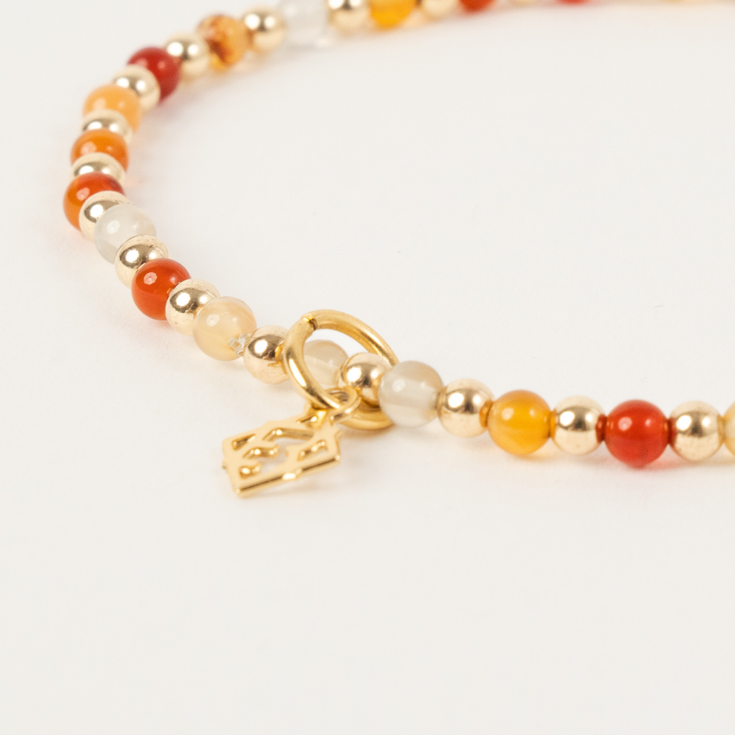 Bracelet with multicolored beads and a gold charm on a white background