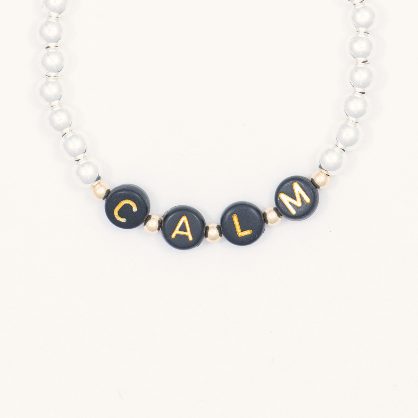 Bracelet with black beads spelling 'CALM' on a white background