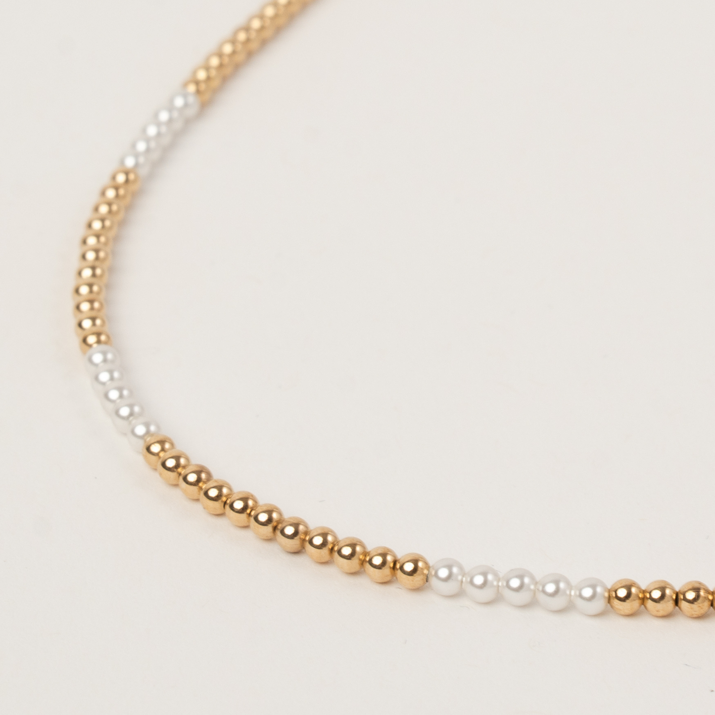 Necklace with gold and white beads on a light background