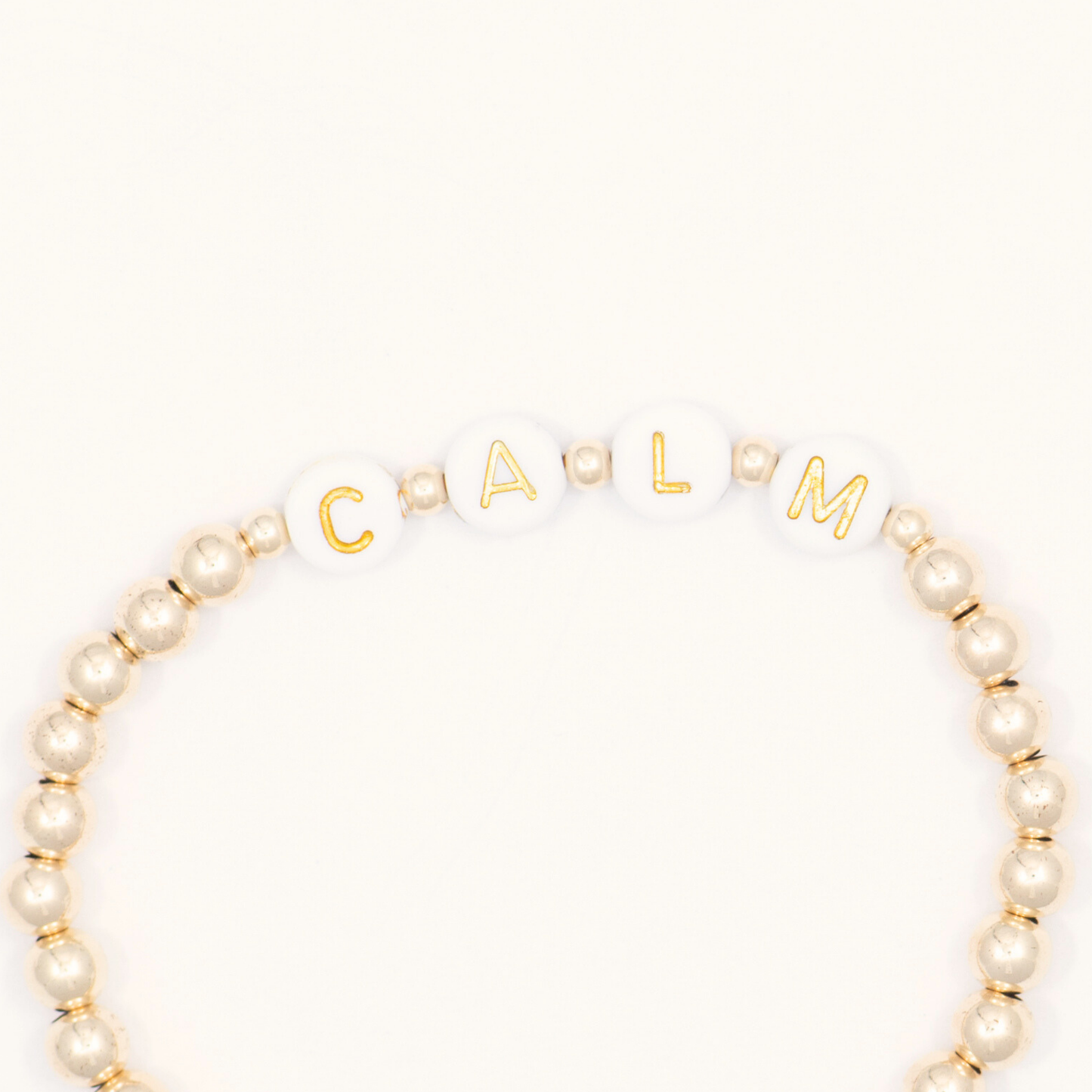 Beaded bracelet with gold letter beads spelling 'CALM' on a white background