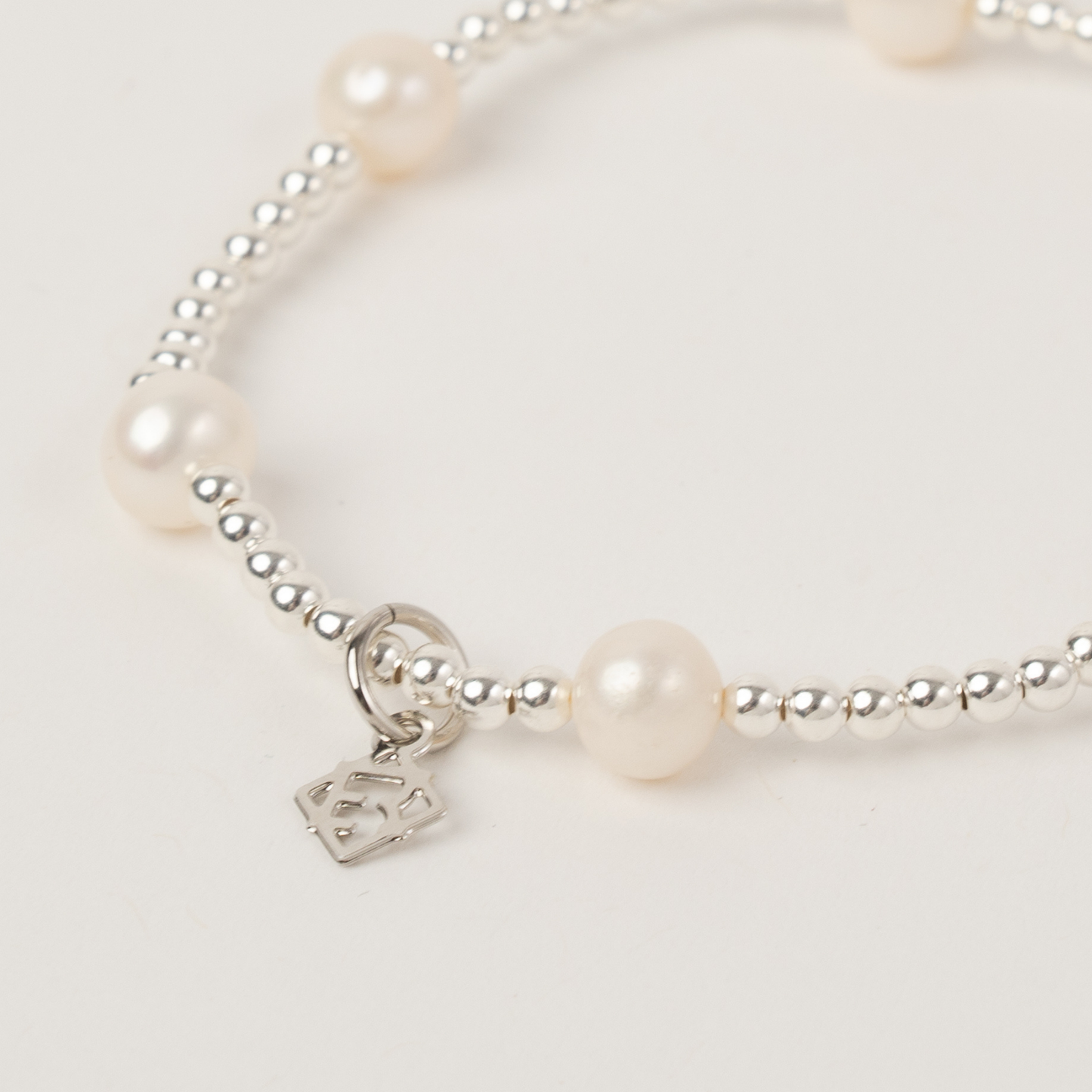 Pearl bracelet with a silver charm on a light background