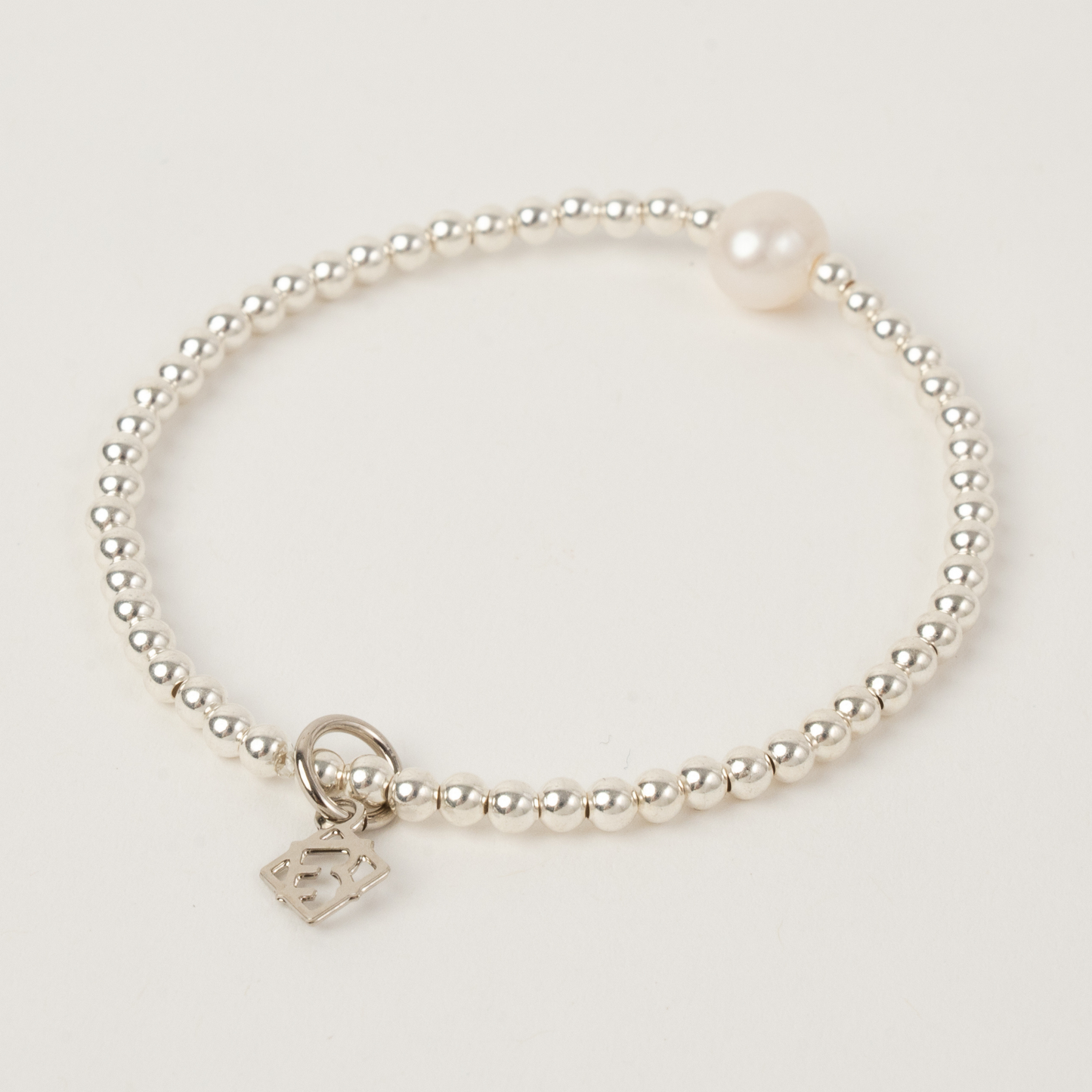 Pearl bracelet with a silver clasp on a light gray background