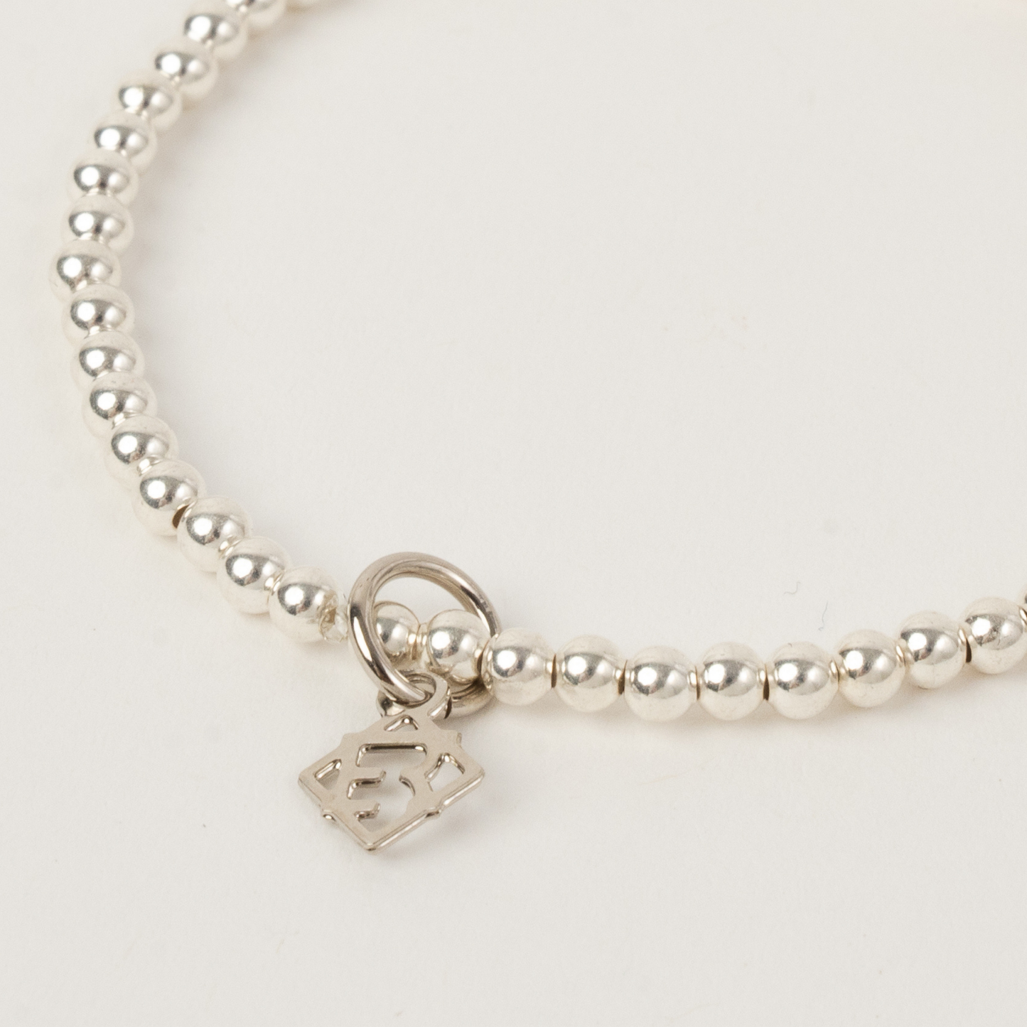 Silver beaded bracelet with a heart-shaped tag on a light gray background