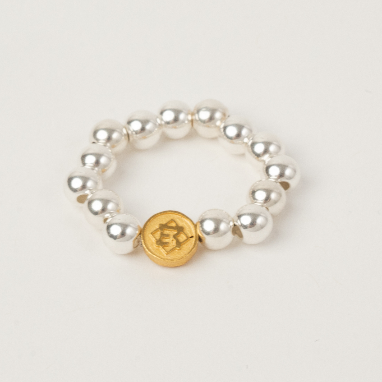 Pearl bracelet with a gold charm on a light gray background