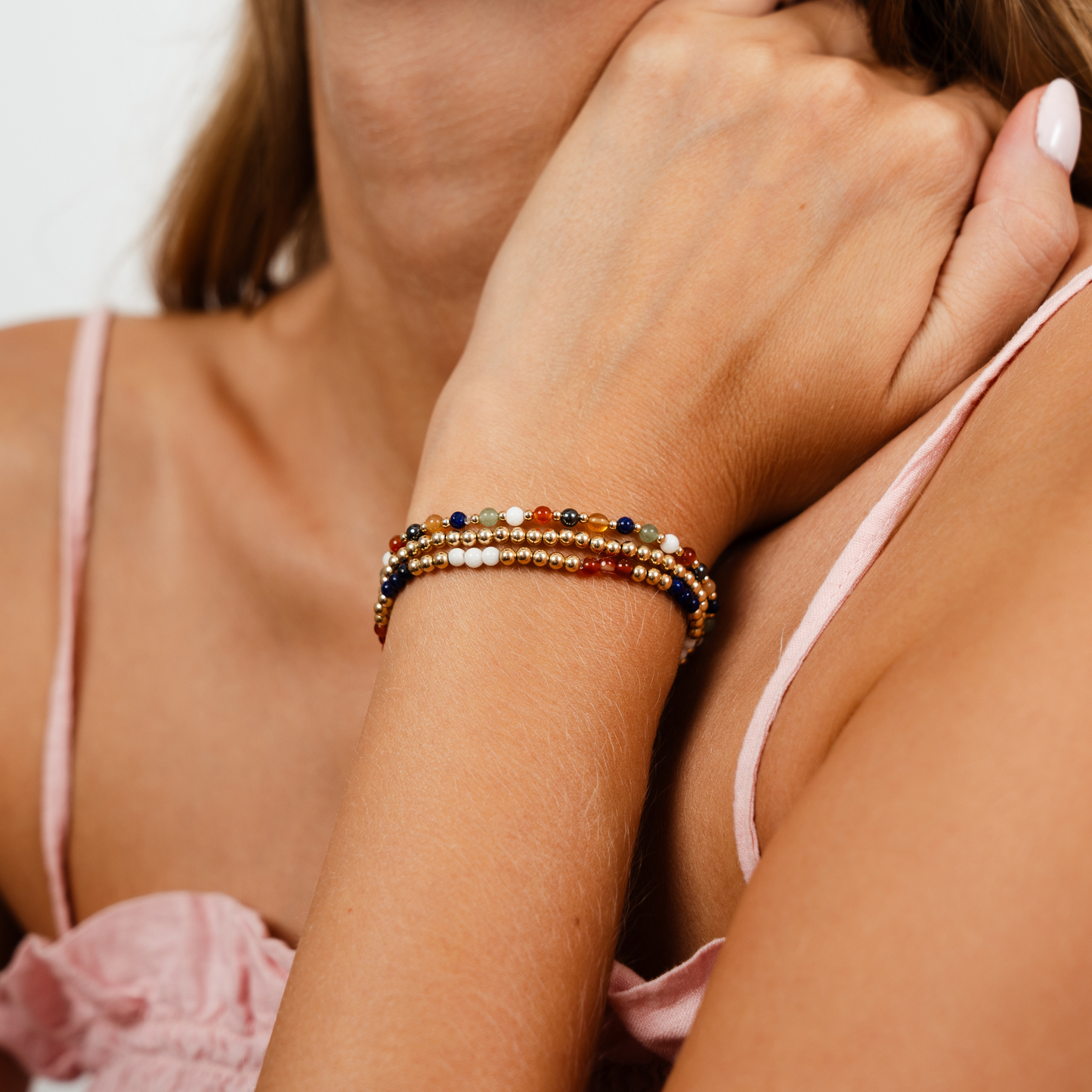 Close-up of a woman's arm wearing a colorful beaded bracelet with a blurred background.