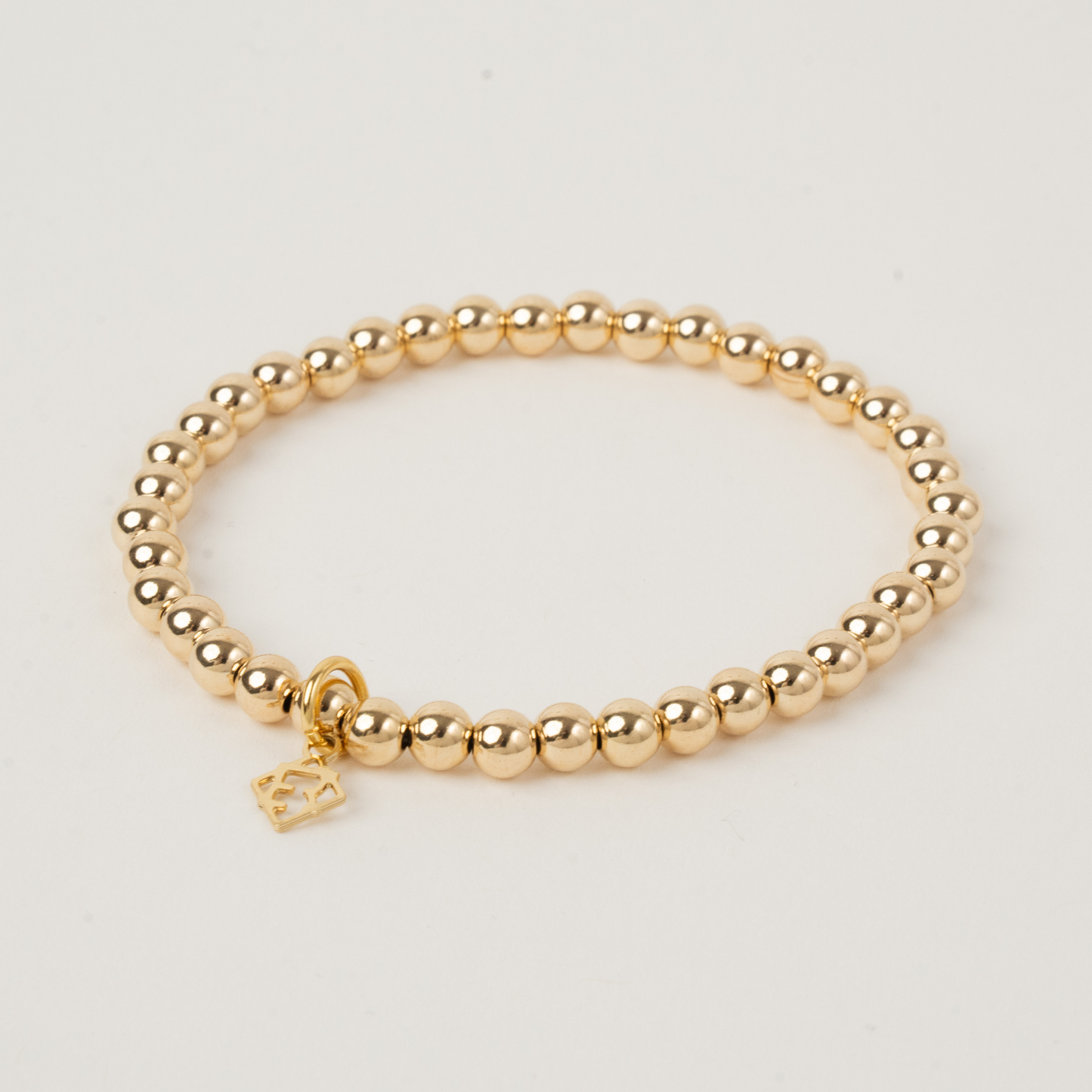 Gold beaded bracelet with a gold clasp on a light gray background