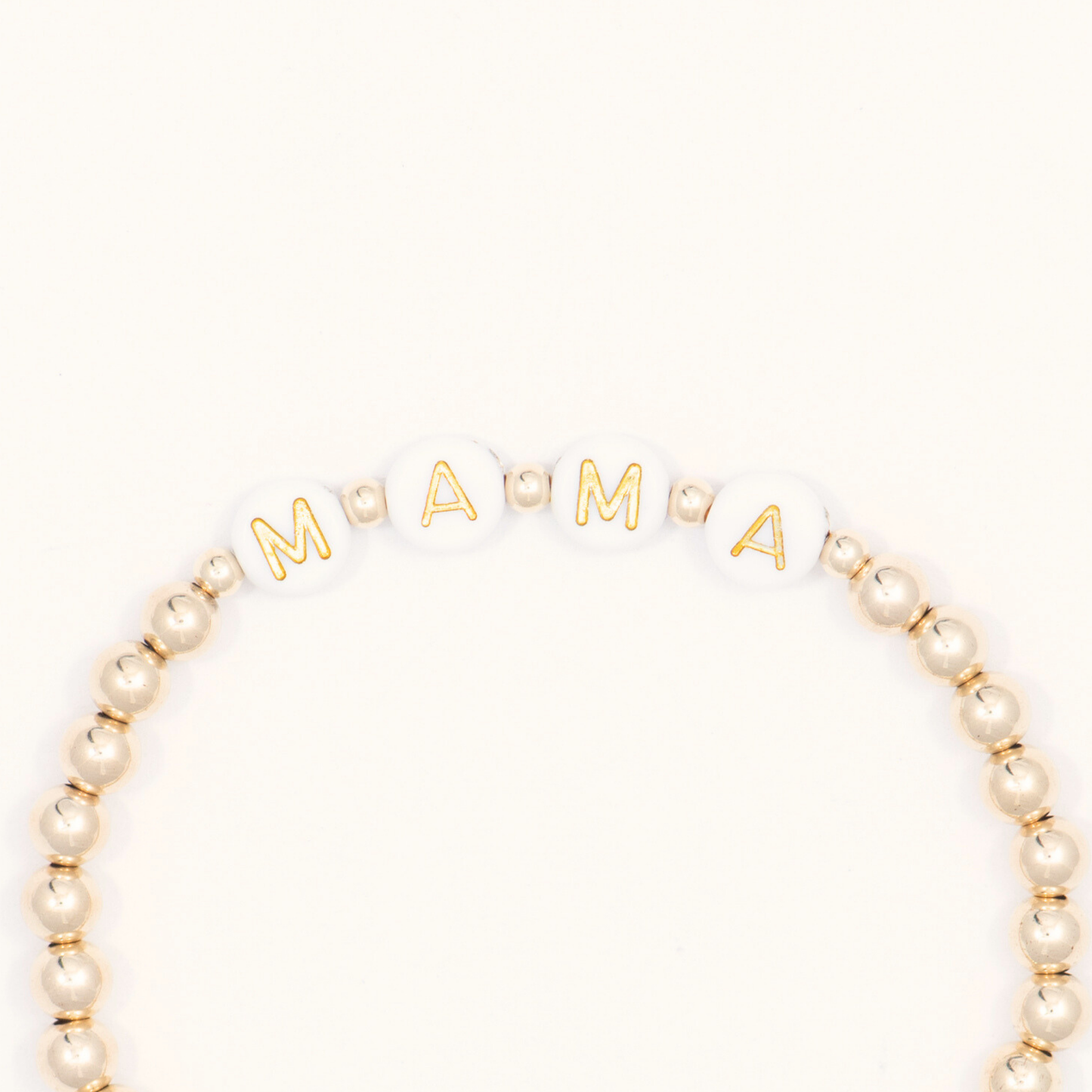 Gold and beaded bracelet with 'MAMA' letters on a white background