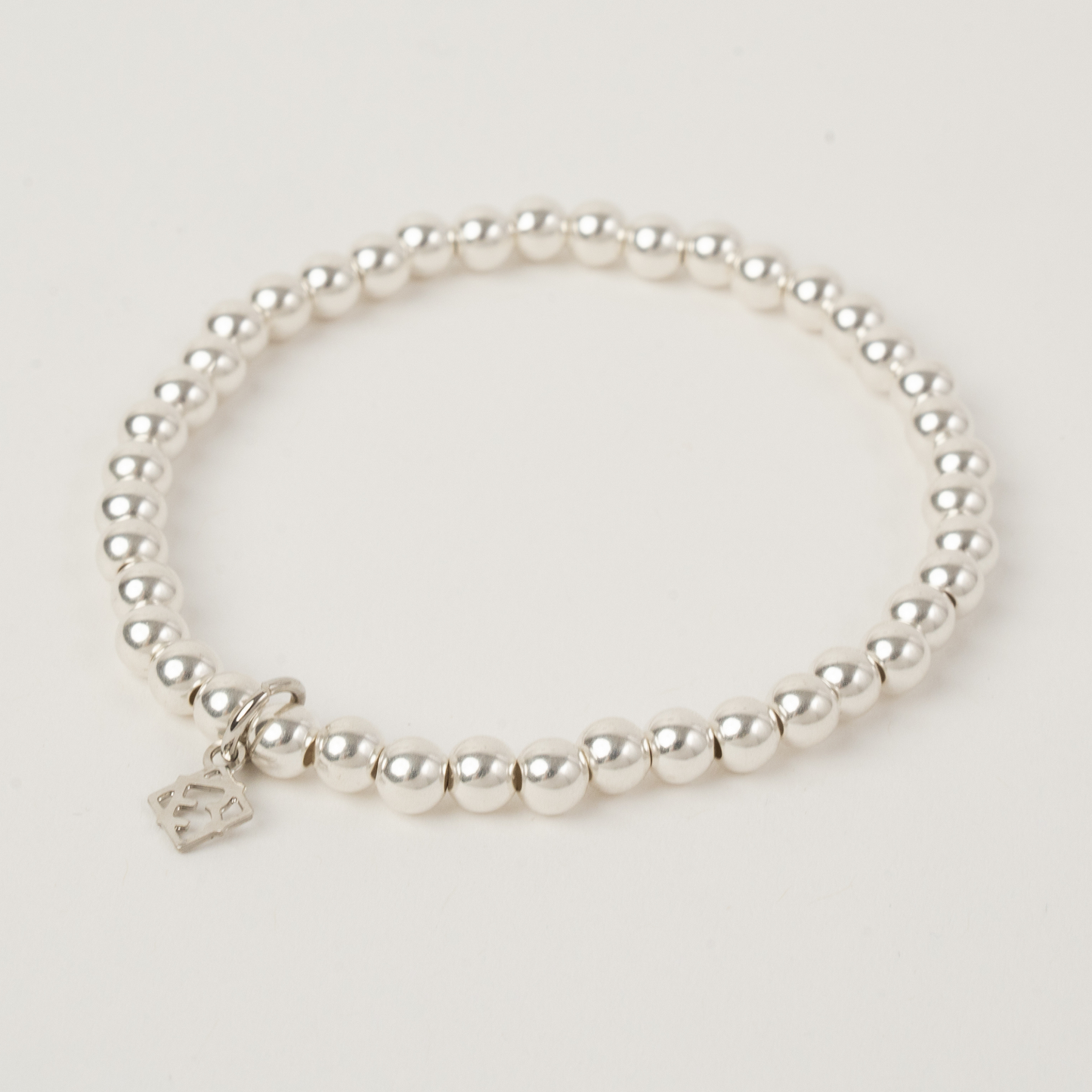 Pearl bracelet with a silver clasp on a light gray background
