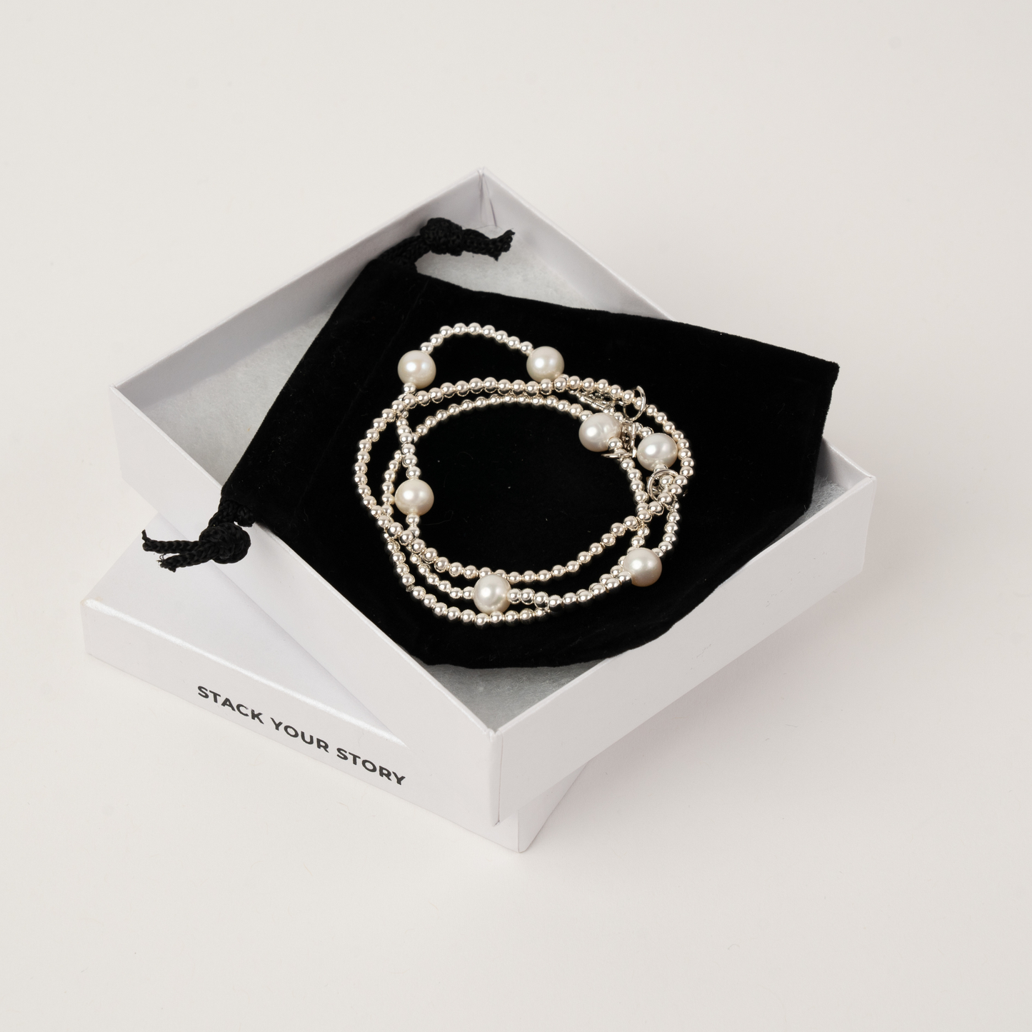 Pearl bracelet in a white box with 'Stack Your Story' branding on a light gray background