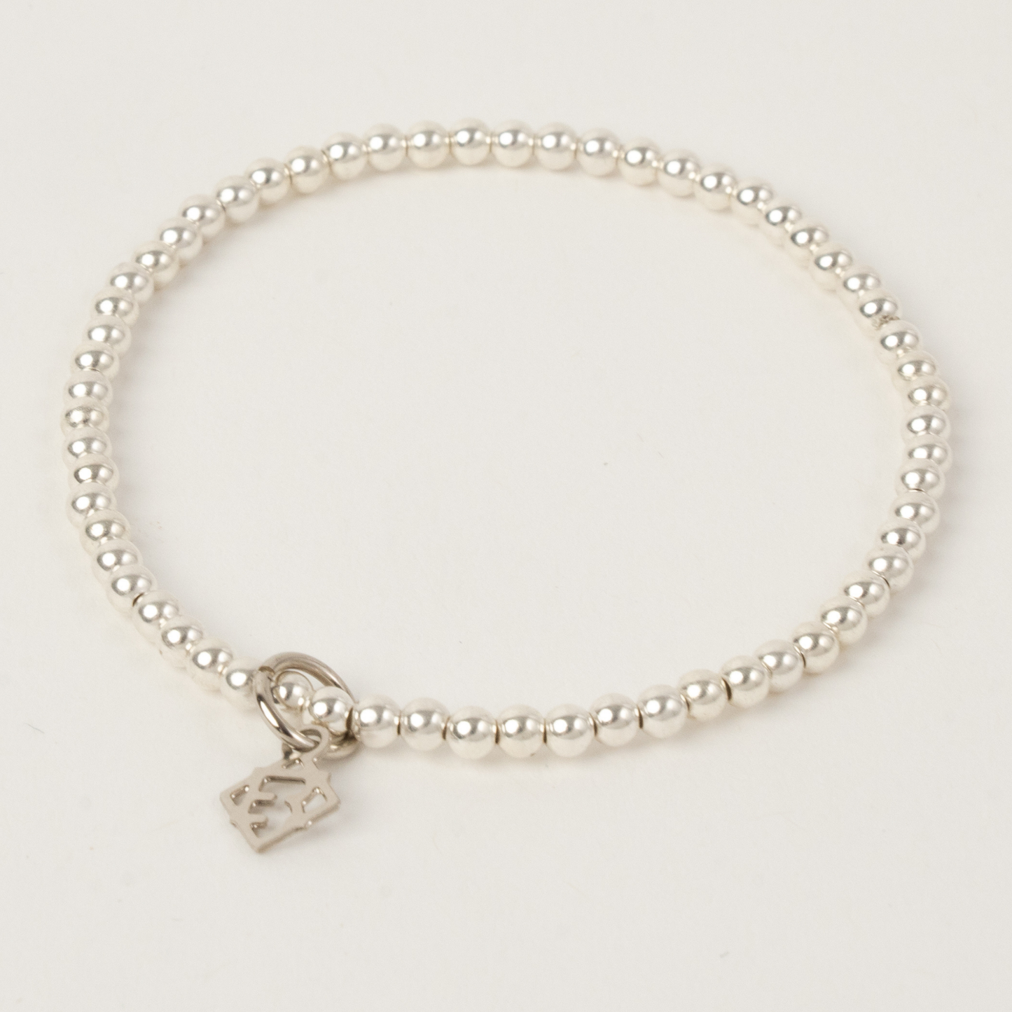 Pearl bracelet with a heart-shaped charm on a light gray background