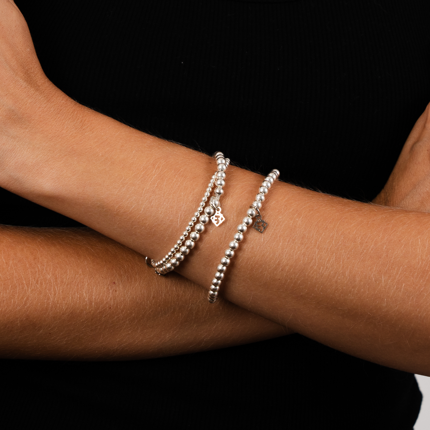 Silver bracelets on a person's wrist against a black background