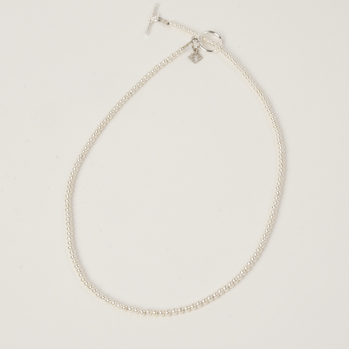 Silver necklace on a light gray background
