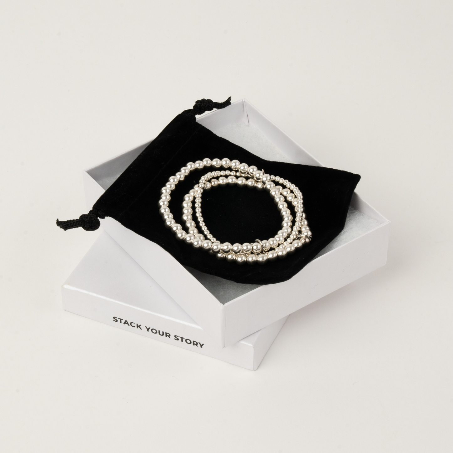 Pearl bracelet on a black drawstring bag inside a white box with 'Stack Your Story' branding.