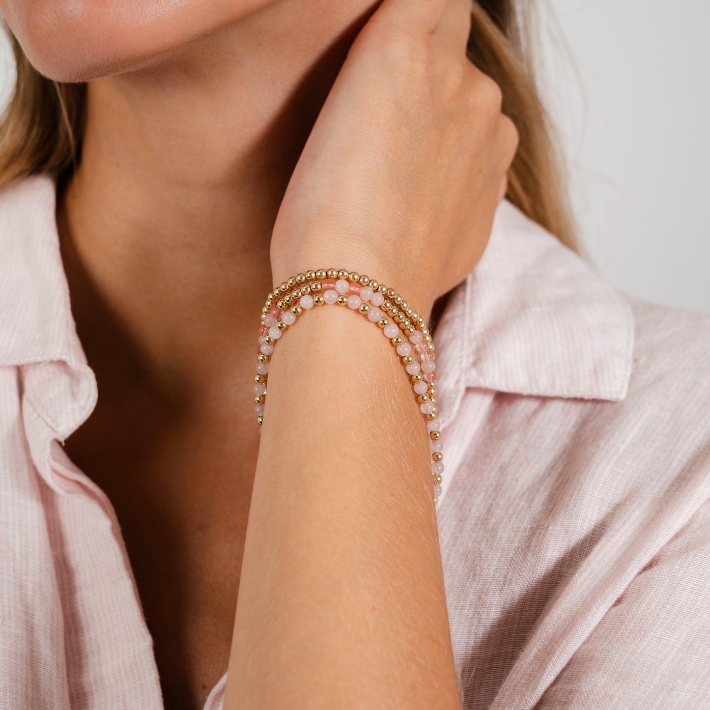 Close-up of a person wearing multiple bracelets on a light background
