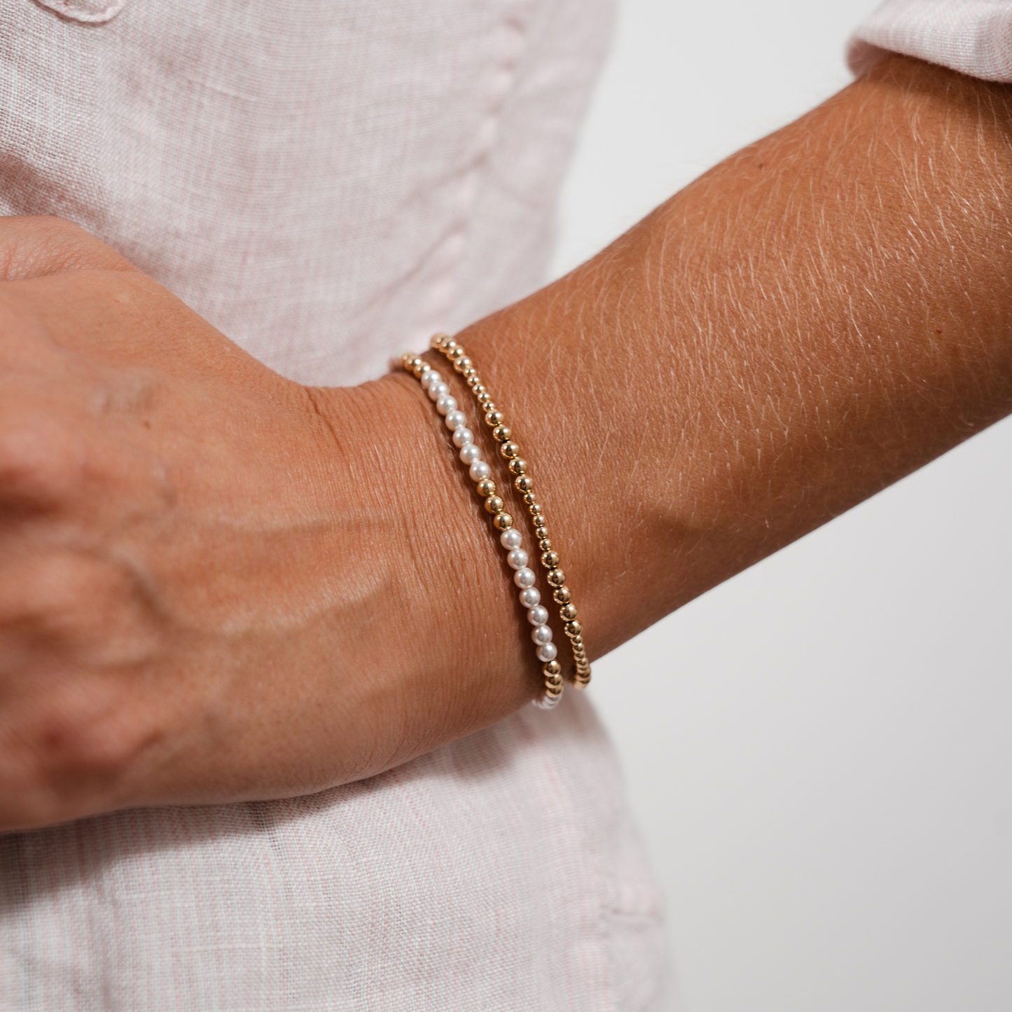 Close-up of a wrist wearing two bracelets on a neutral background