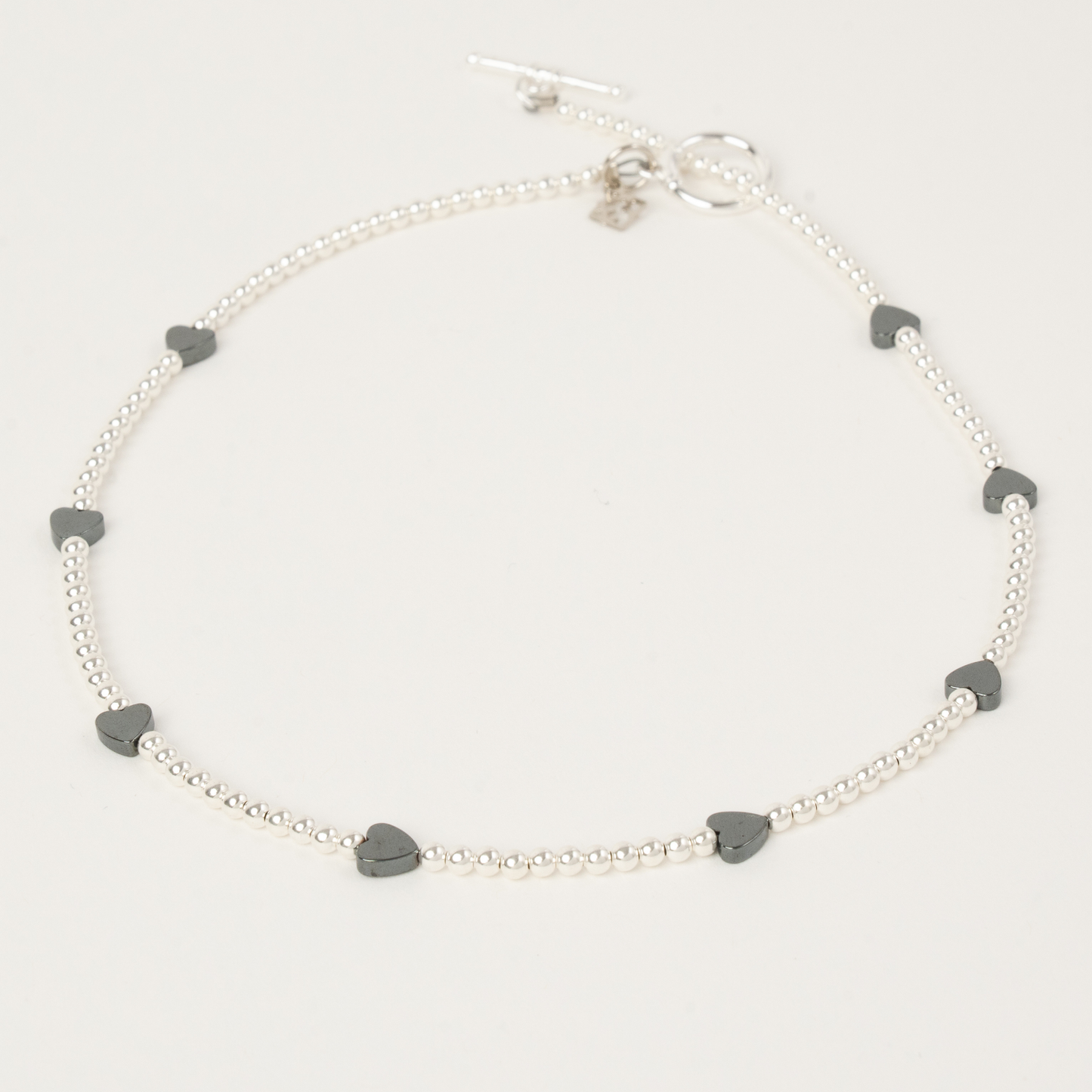 Silver necklace with heart-shaped charms on a light gray background