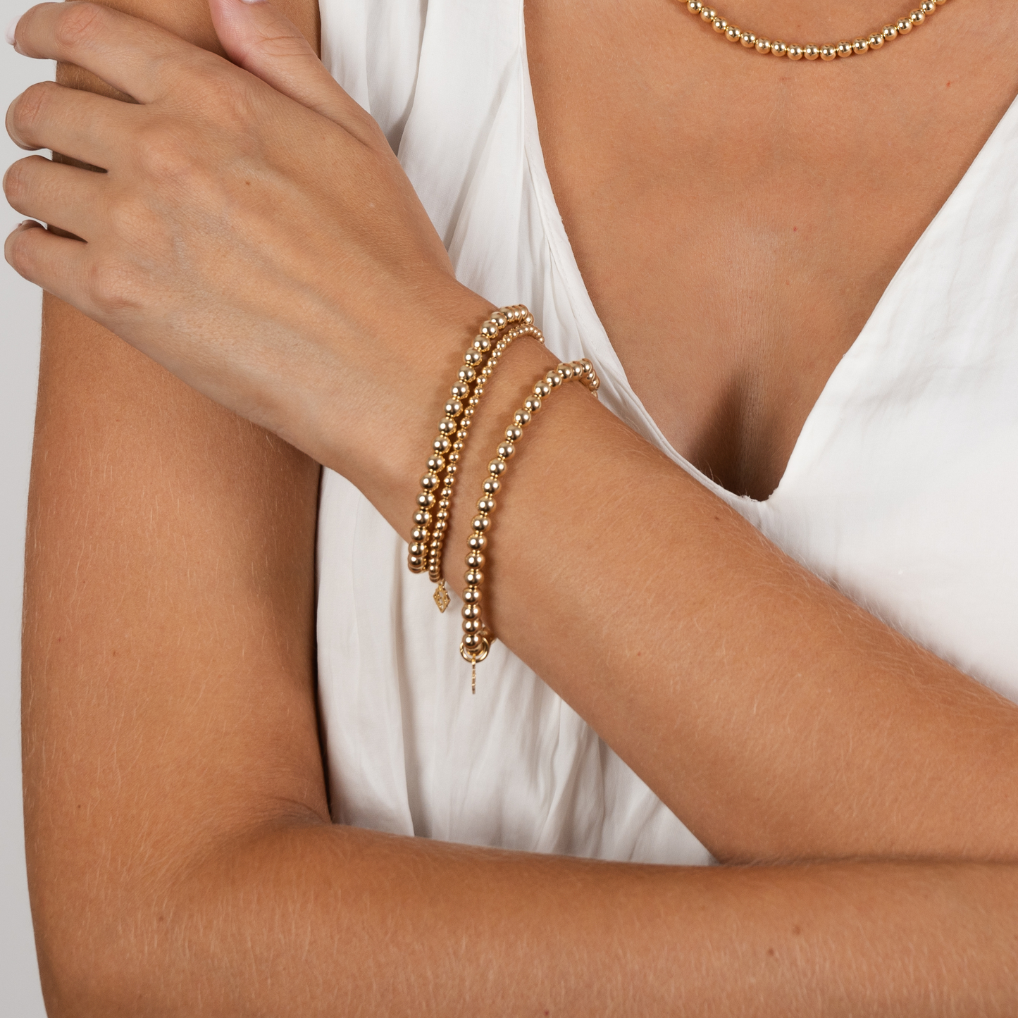 Gold bracelets on a person's wrist with a plain background
