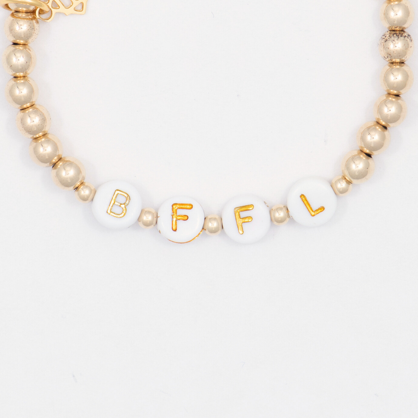 Bracelet with gold and white beads spelling 'BFFL' on a light background