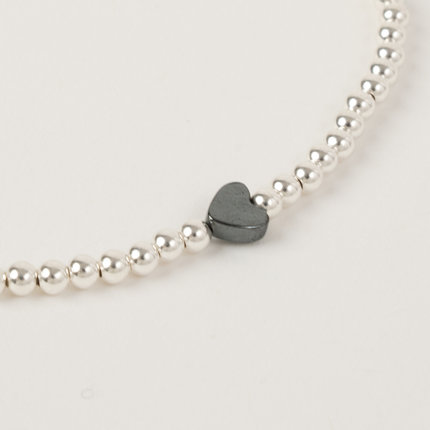 Pearl bracelet with a heart-shaped black stone on a light background