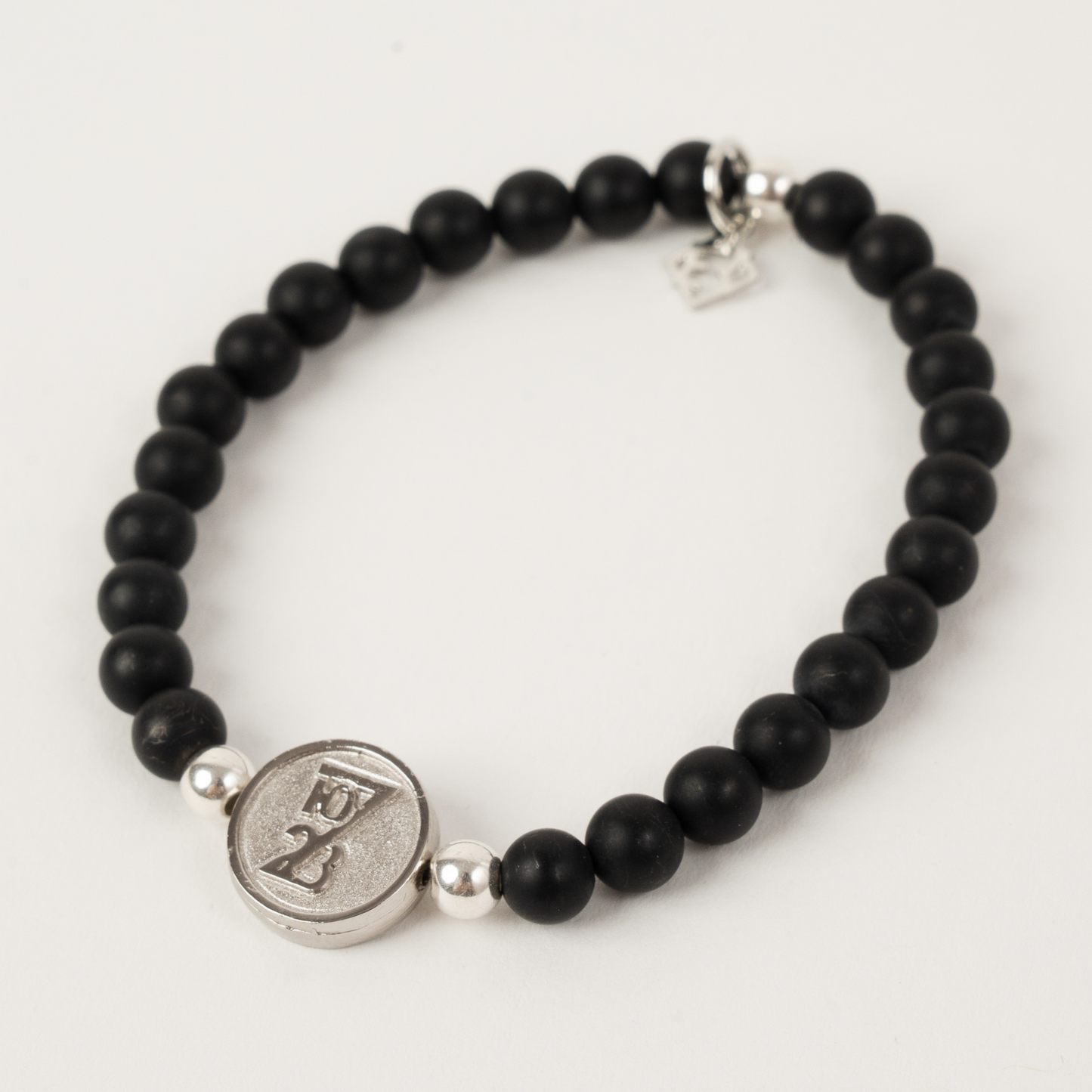 Black beaded bracelet with a silver charm on a white background