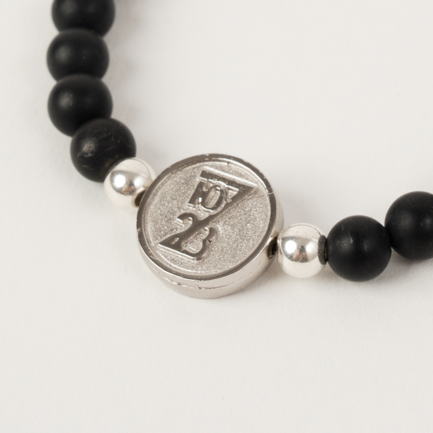 Bracelet with black beads and a silver charm on a white background
