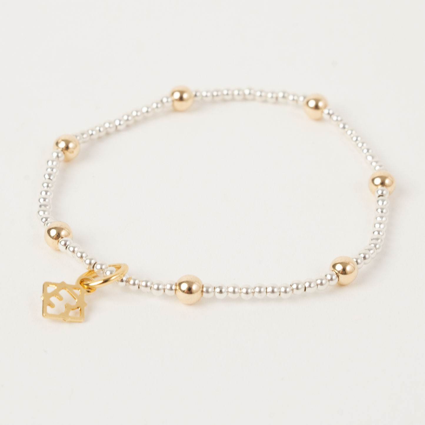 Bracelet with gold and silver beads on a light gray background