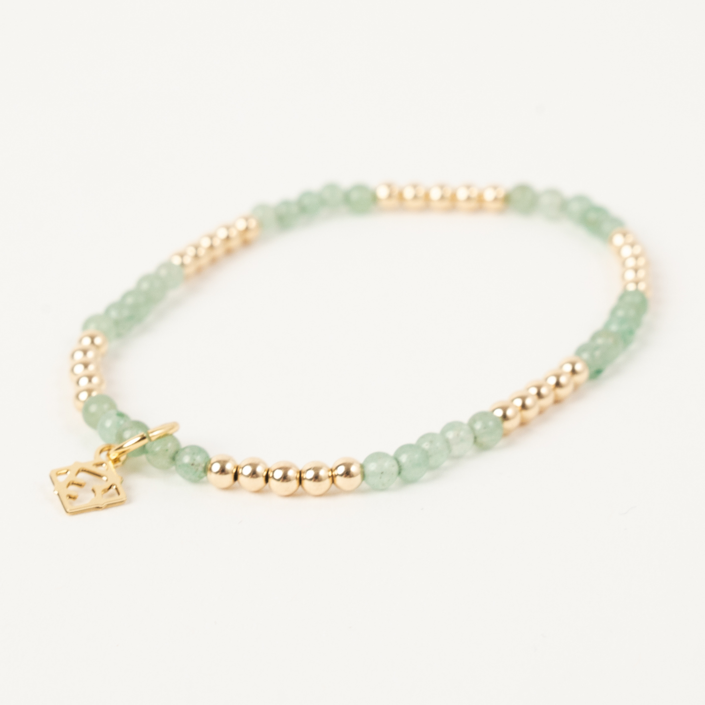 Green beaded bracelet with gold accents on a white background