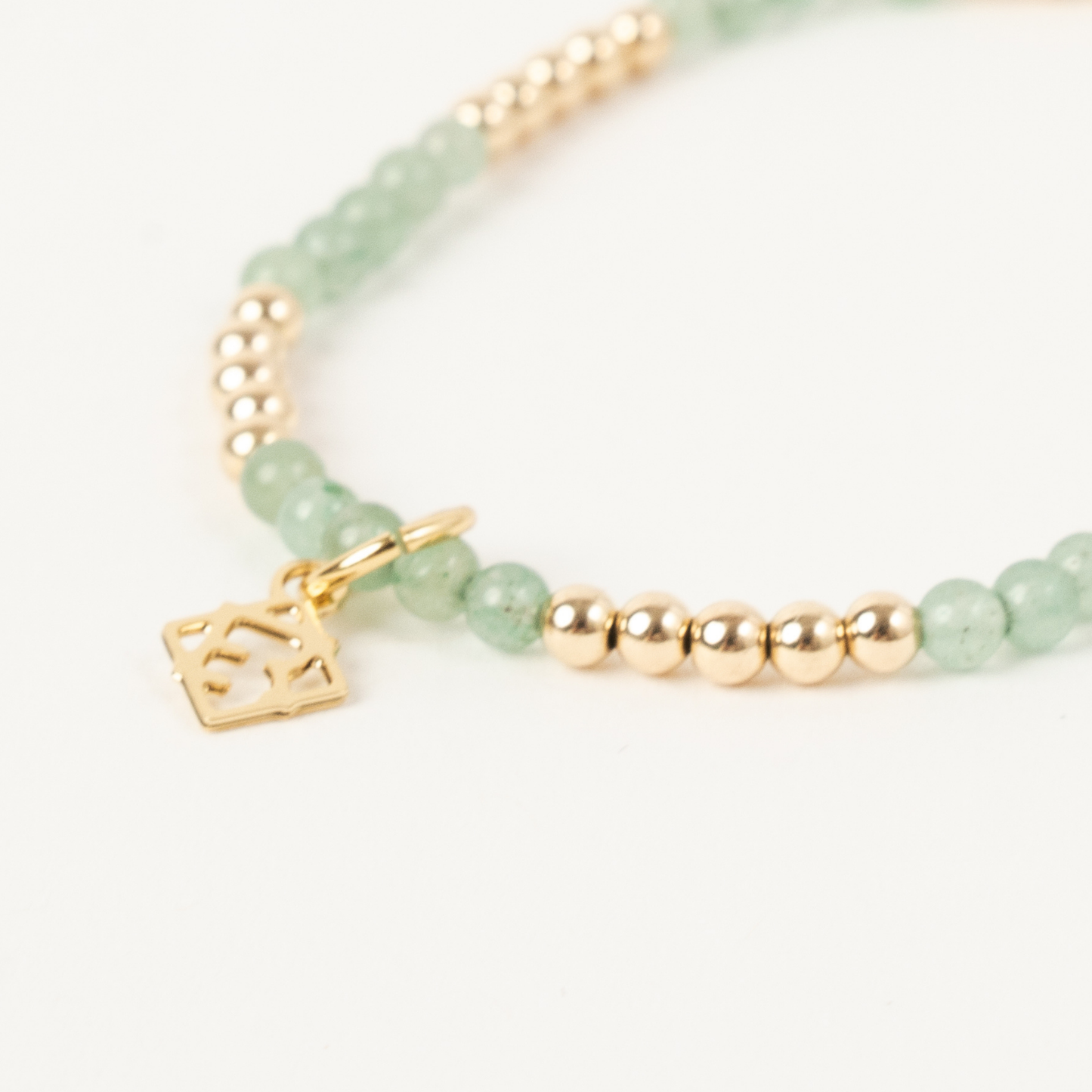 Green beaded bracelet with gold accents on a white background