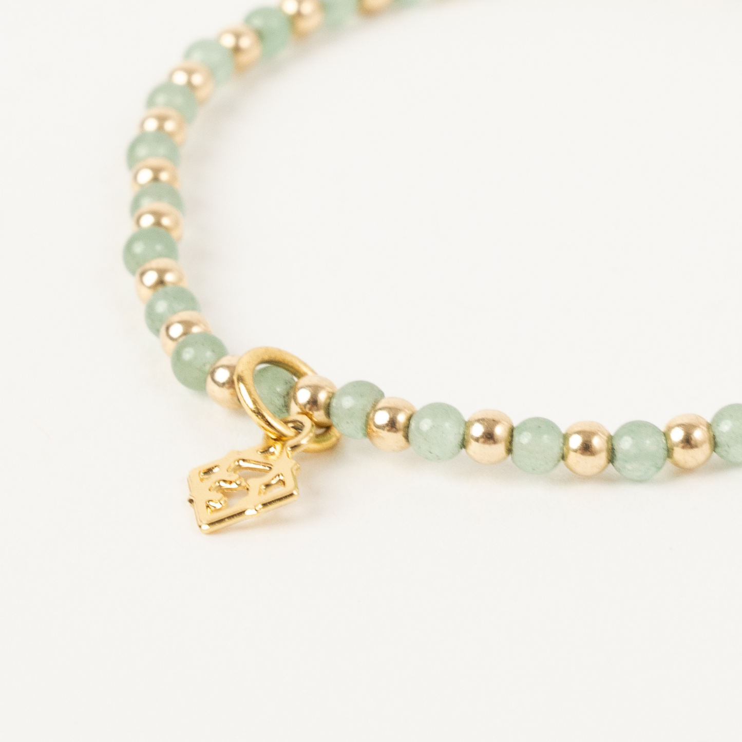 Beaded bracelet with gold charm on a white background