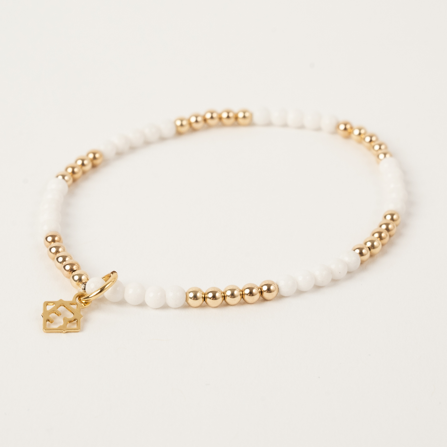 Bracelet with gold beads and a heart charm on a white background