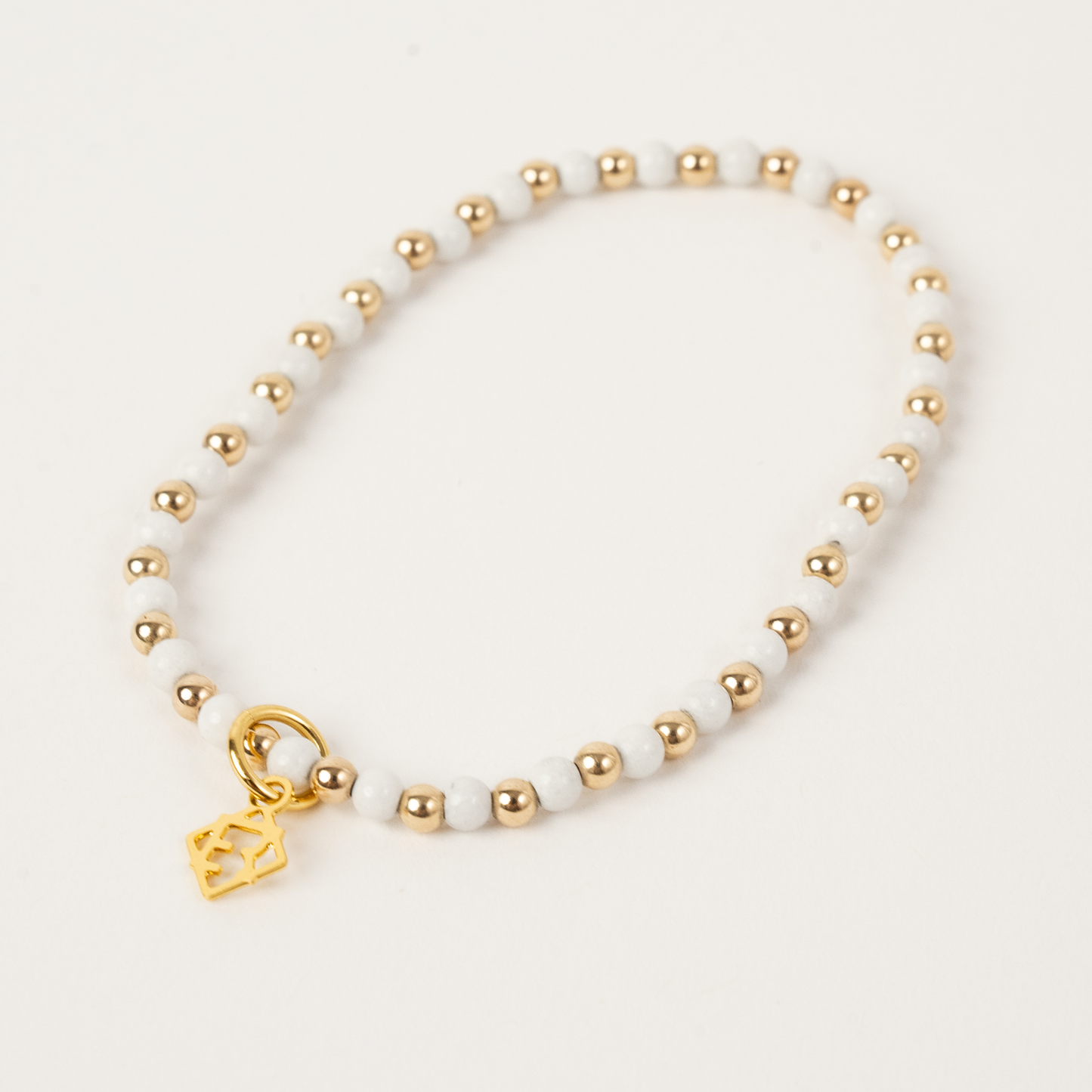 Bracelet with gold beads and a heart charm on a white background