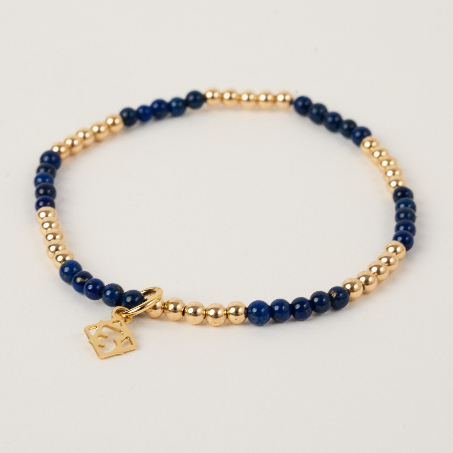 Bracelet with blue beads and gold accents on a light gray background
