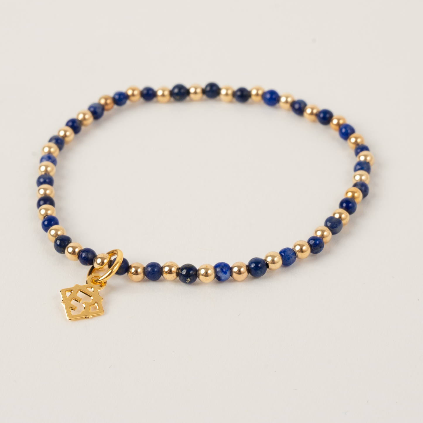 Bracelet with blue beads and gold accents on a light gray background