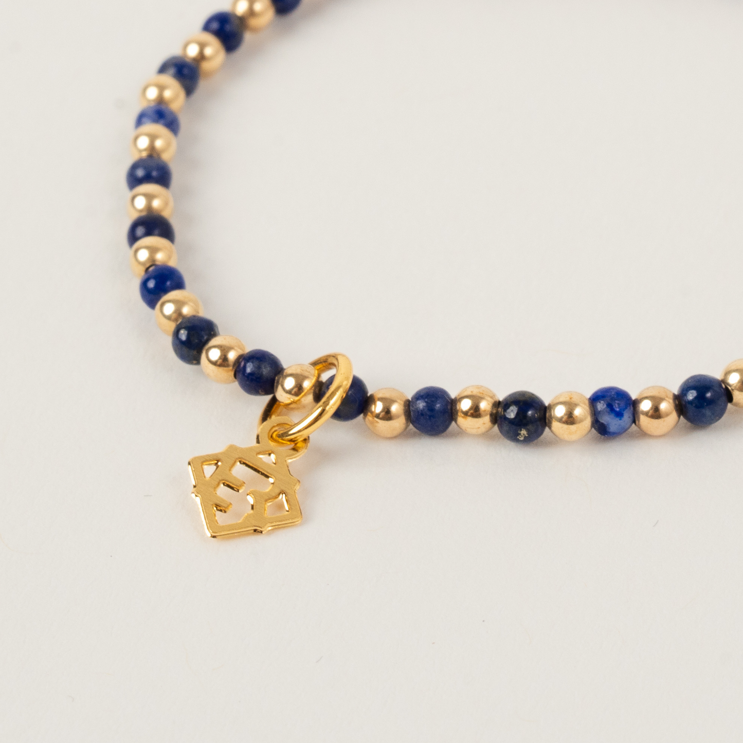 Bracelet with blue beads and gold accents on a light gray background