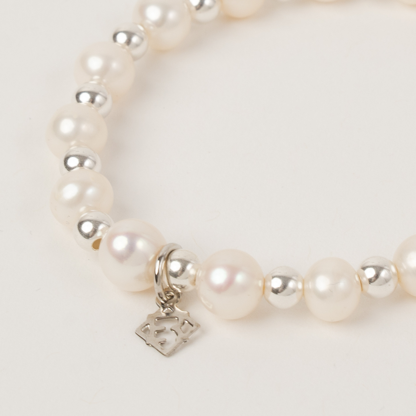 Pearl bracelet with silver beads and a heart-shaped charm on a light background