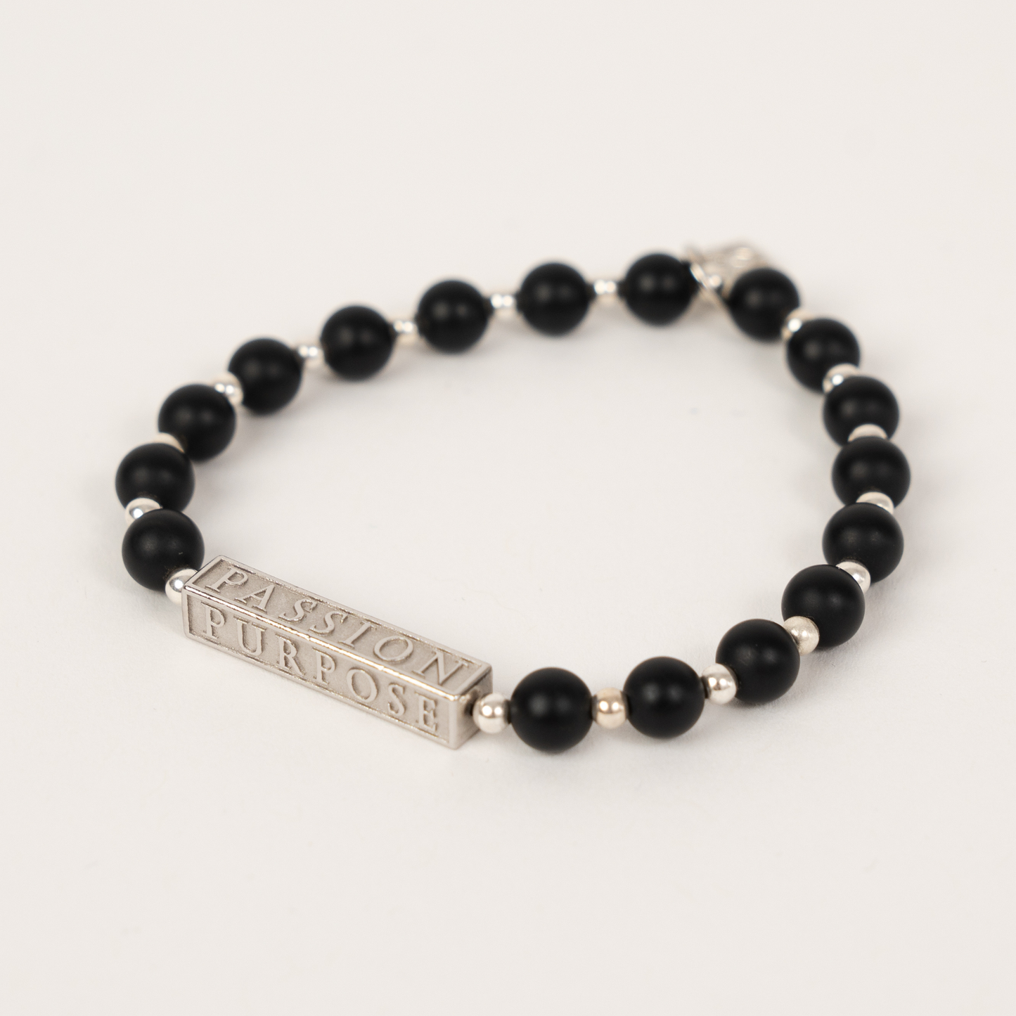Black and silver beaded bracelet with rotating charm that says PASSION POWER PURPOSE STACKED