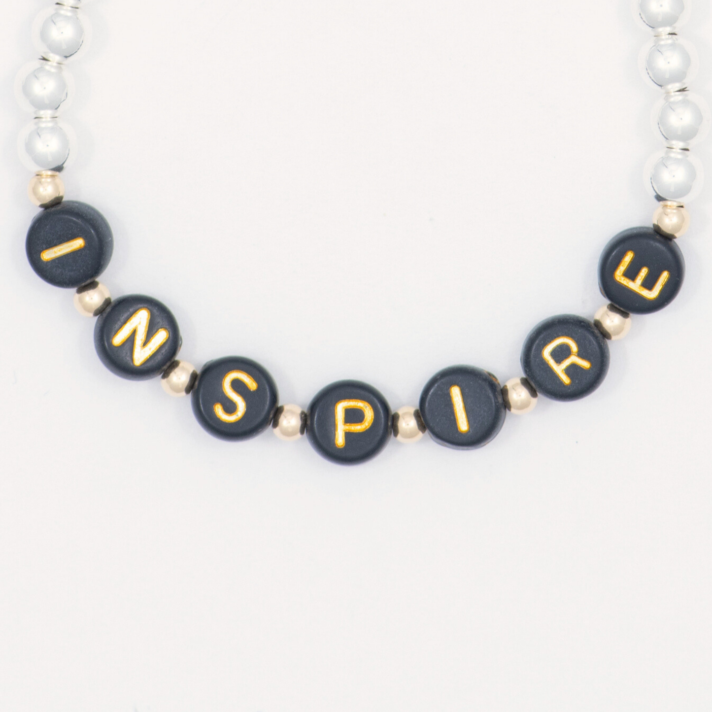 Bracelet with black beads spelling 'INSPIRE' on a white background