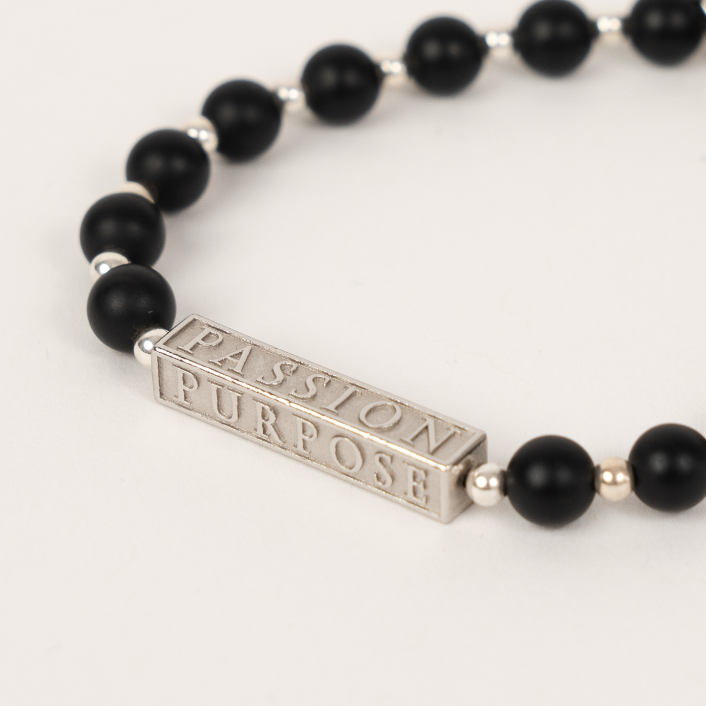 Black beaded bracelet with a silver bar featuring 'Passion Purpose' on a white background