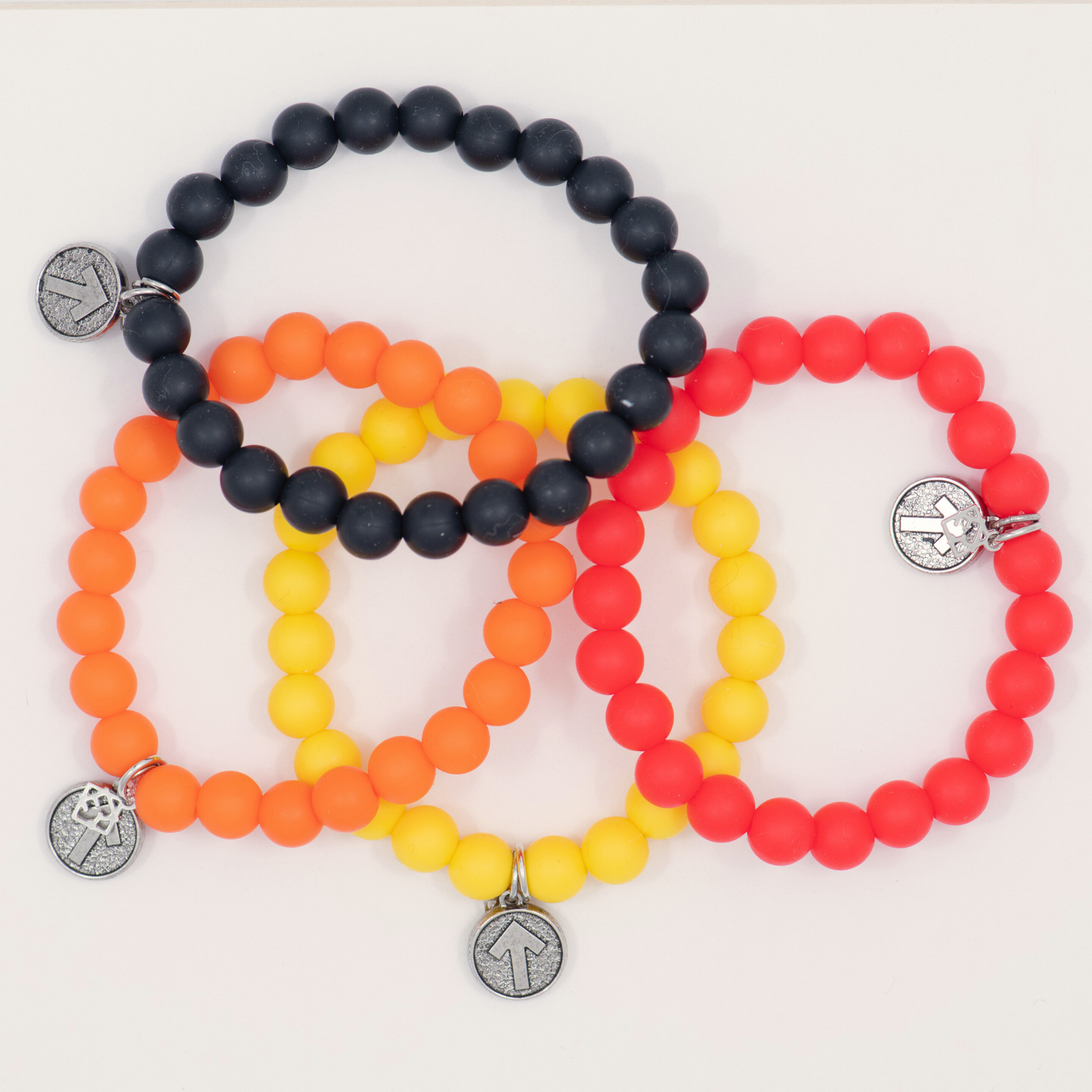 Set of four beaded bracelets in black, orange, yellow, and red on a white background