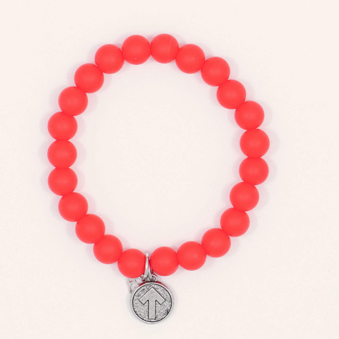 Red beaded bracelet with a silver charm on a white background