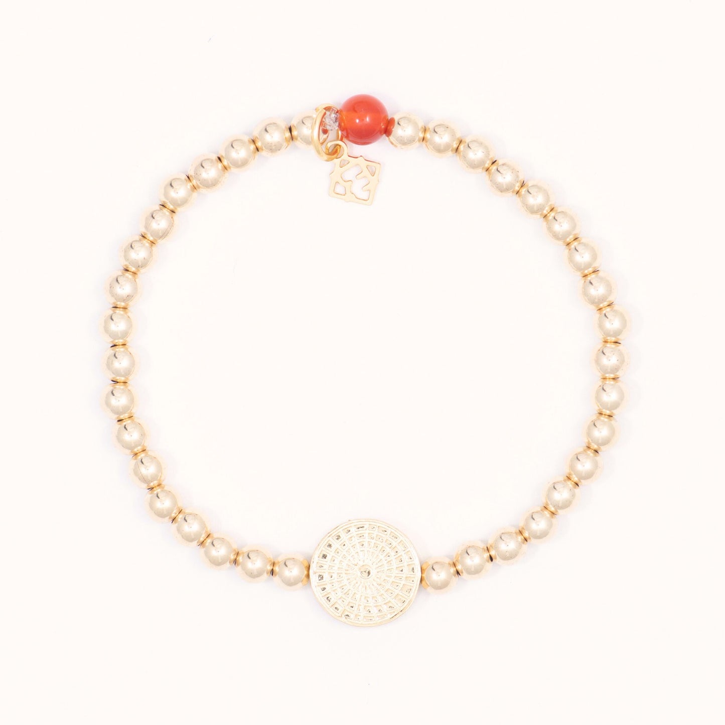 Gold bracelet with a red bead on a white background