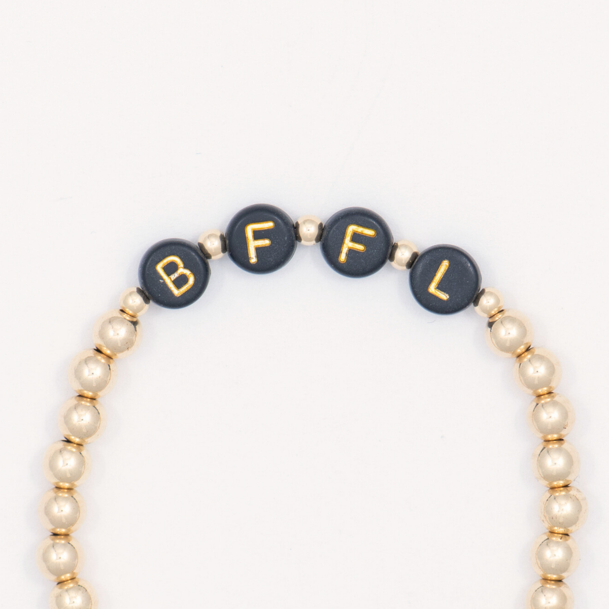 Close-up of black letter beads spelling BFFL on the 14K gold-filled Thoughtful bracelet