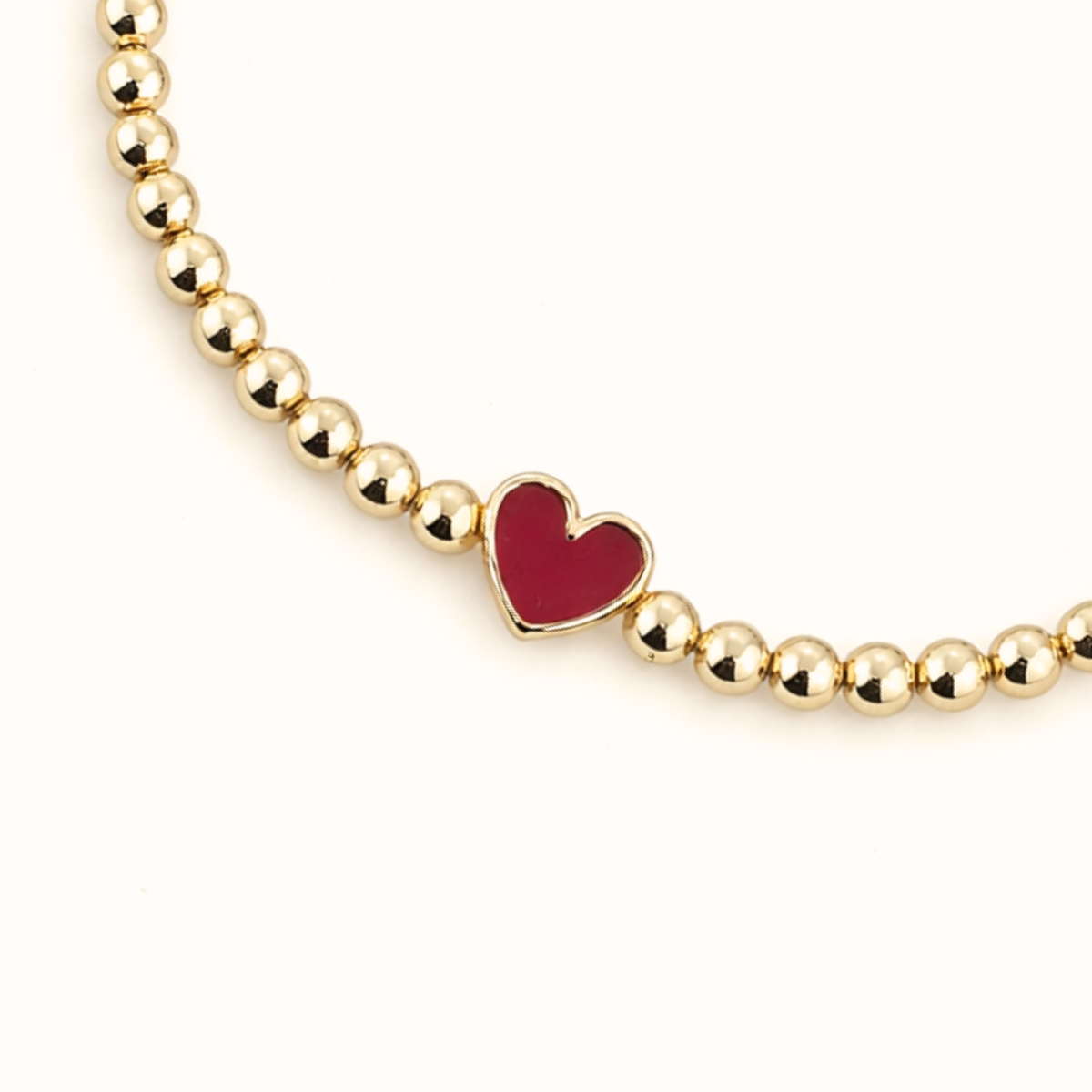 Close-up of the cherry red enamel heart and 3mm 14K gold-filled beads on the Cherry Happy Heart Bracelet