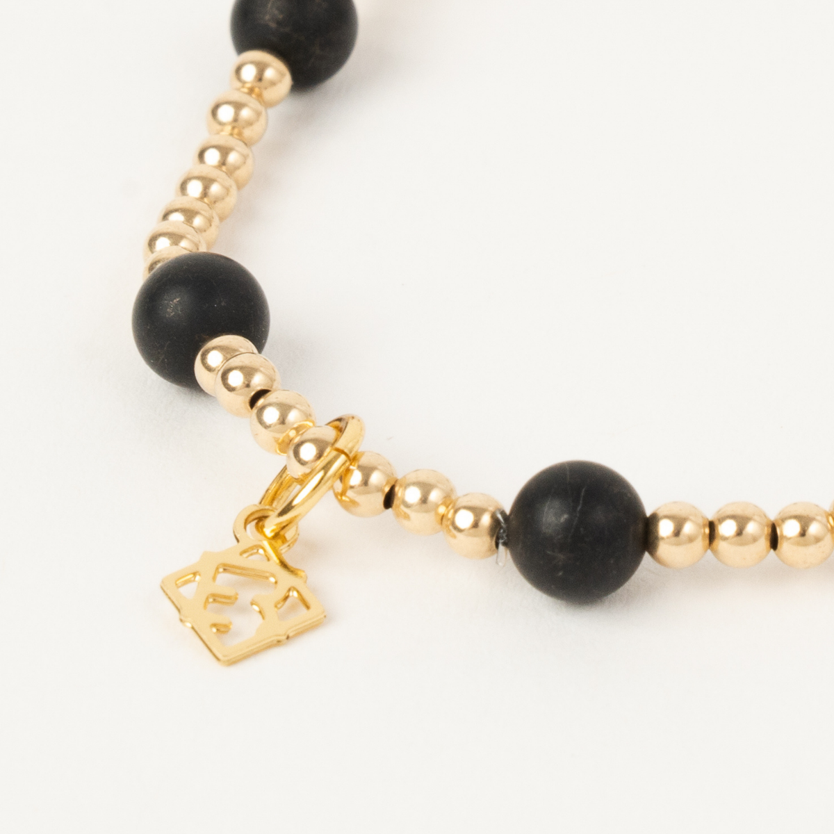 Close-up of the Maverick Edge Bracelet with 3mm 14K gold-filled beads, 6mm black onyx accents and an ElyseRyan charm