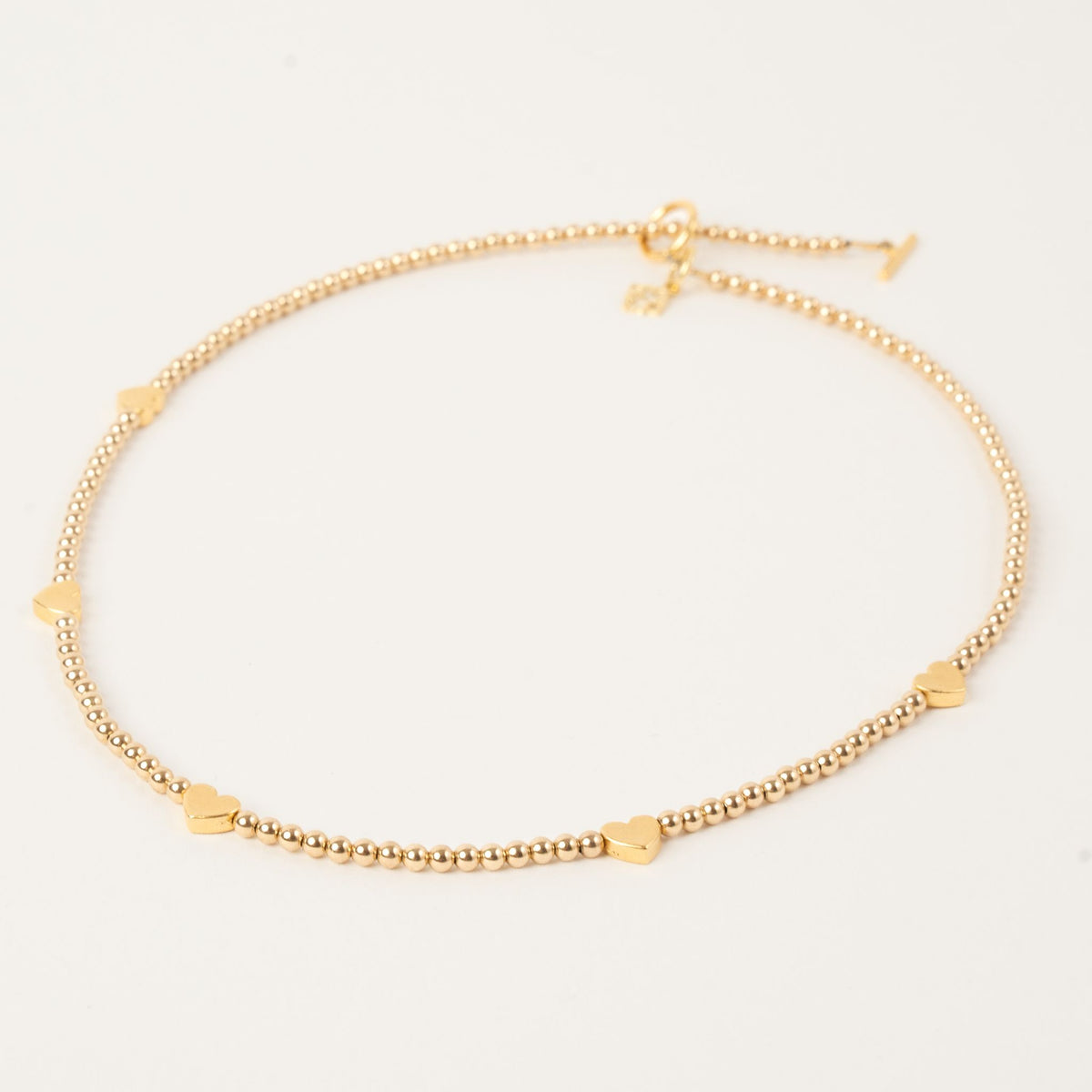 Golden Heart Necklace with 3mm 14K gold-filled beads, five golden hearts, a toggle clasp and signature ER charm