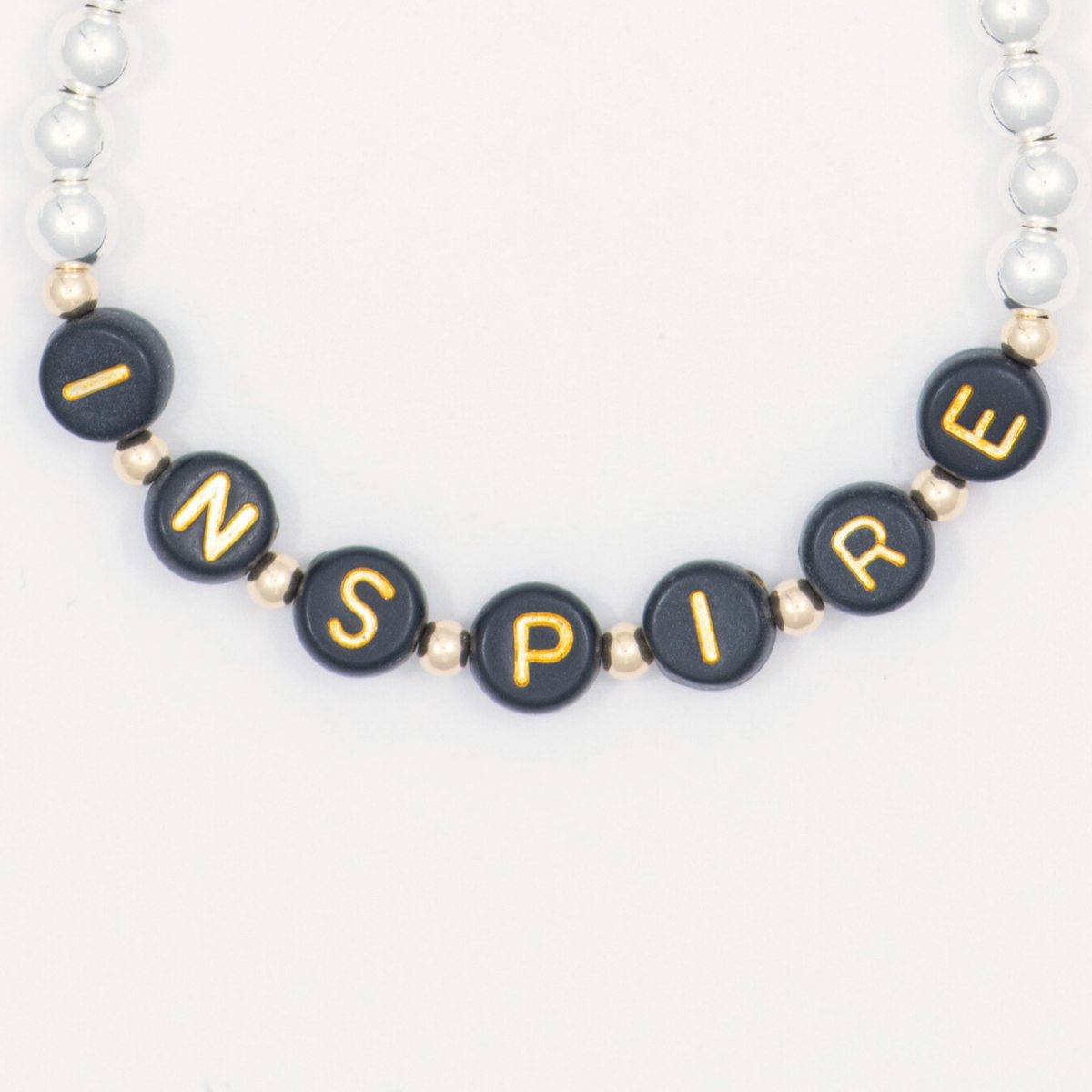 Close-up of black letter beads spelling INSPIRE on the silver-filled Thoughtful bracelet