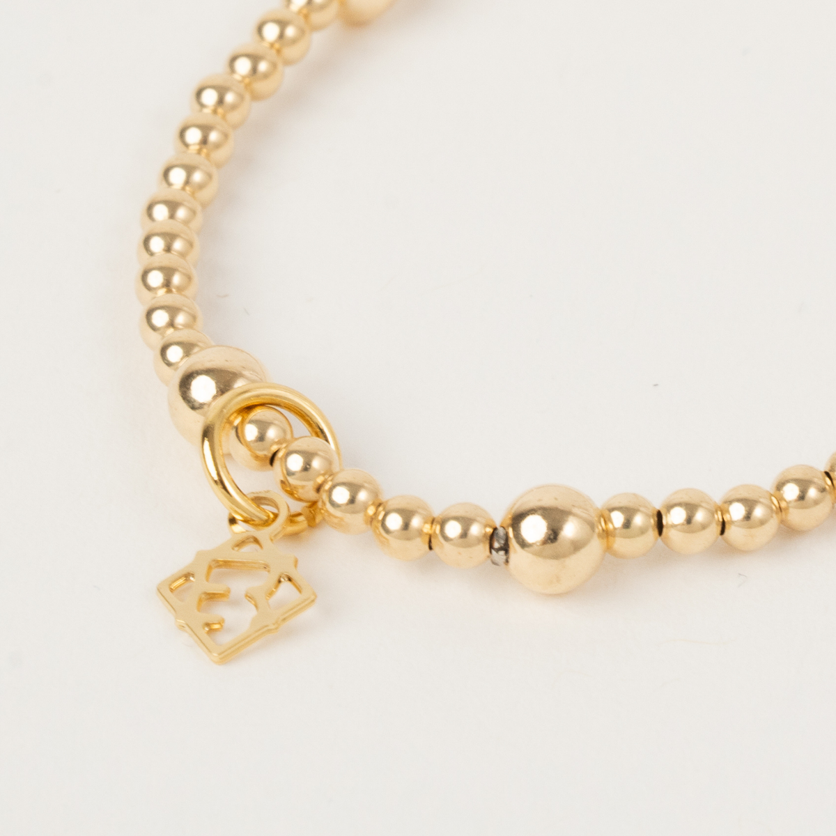 Close-up of the Lennon Gold Bracelet with 3mm and 5mm 14K gold-filled beads and an ElyseRyan charm