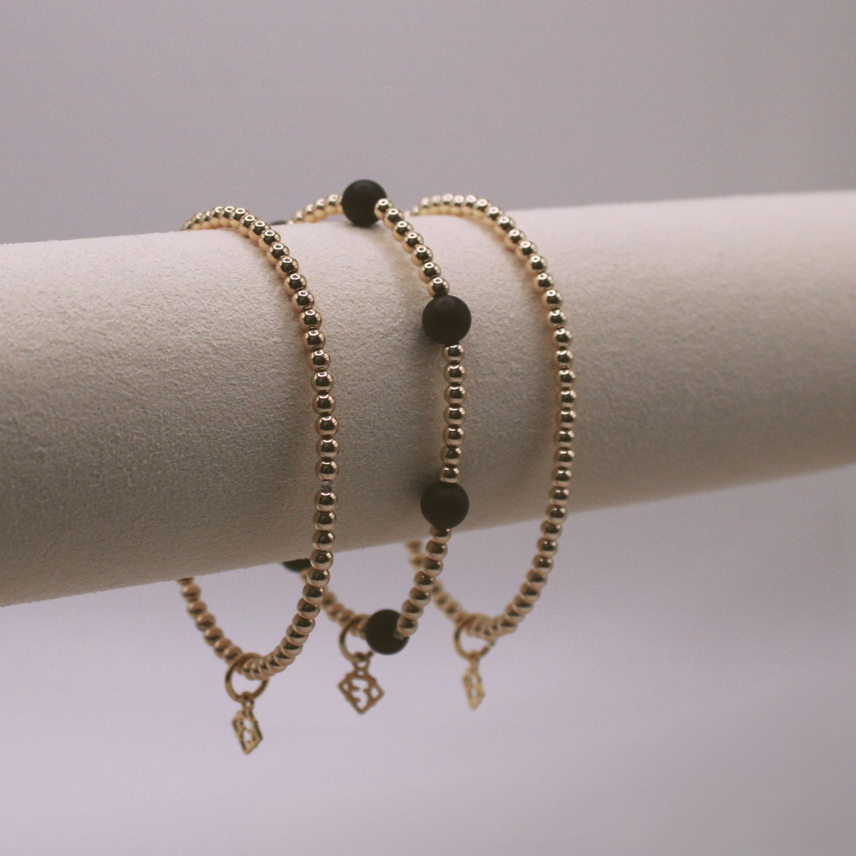 Maverick Edge Bracelet Stack with three 3mm 14K gold-filled bracelets, including one with 6mm black onyx accents
