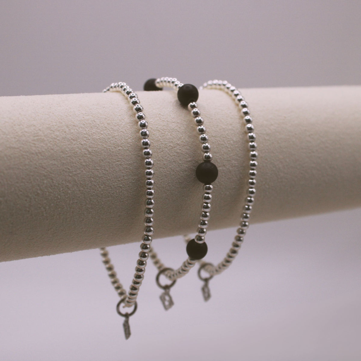 Maverick Edge Bracelet Stack with three 3mm sterling silver bracelets, including one with 6mm black onyx accents